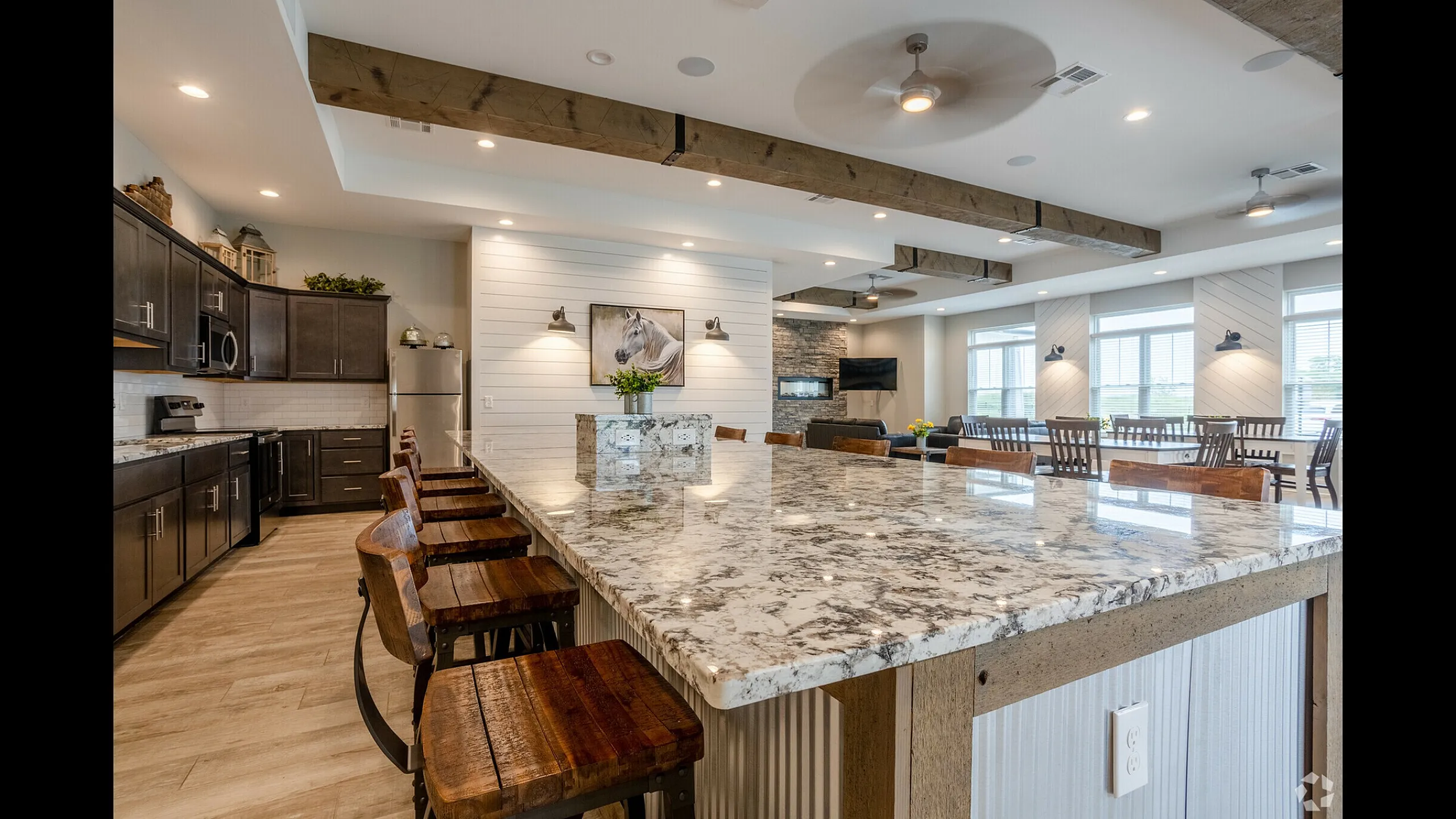 Luxurious open-concept kitchen and living area with a spacious marble countertop island, elegant dark wood cabinets, and inviting natural light.