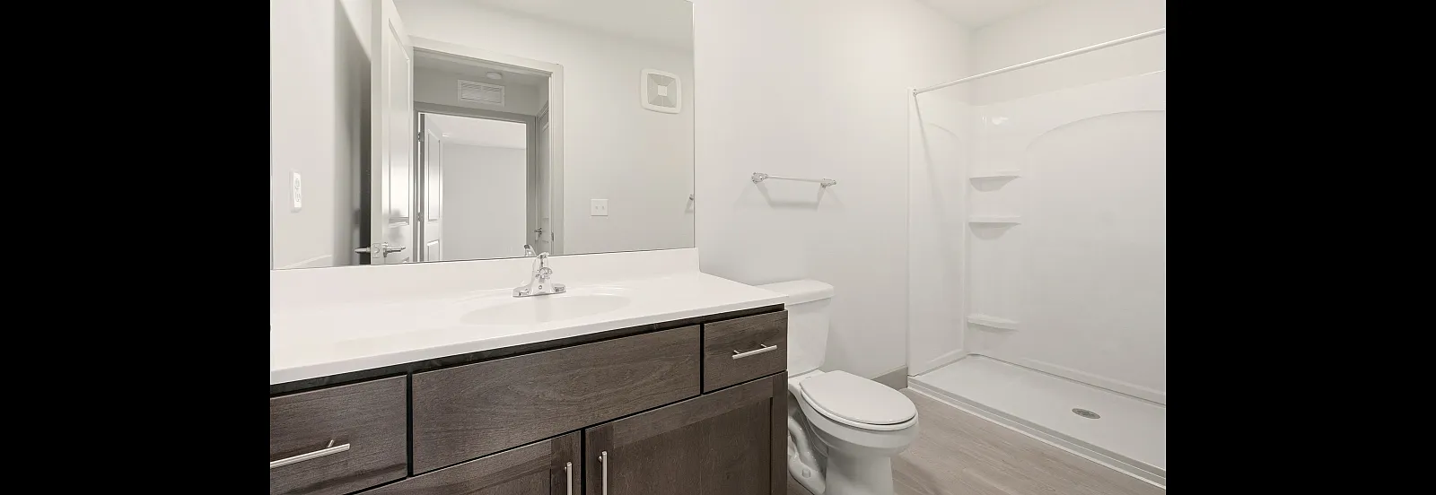 Sleek and modern bathroom showcasing a stylish vanity, spacious mirror, and elegant shower space.