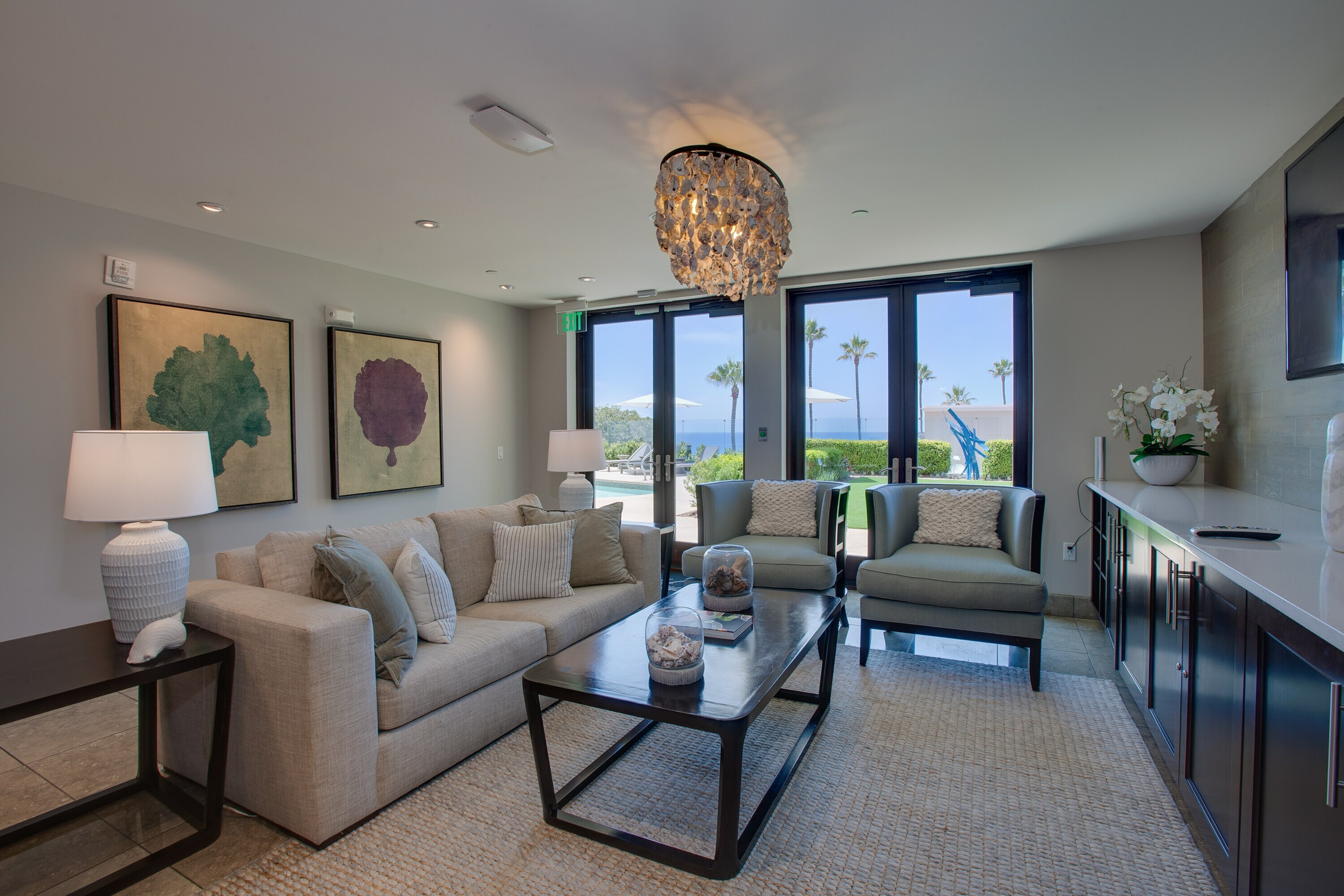 Luxurious living room with elegant decor, plush seating, and stunning ocean views through large glass doors.