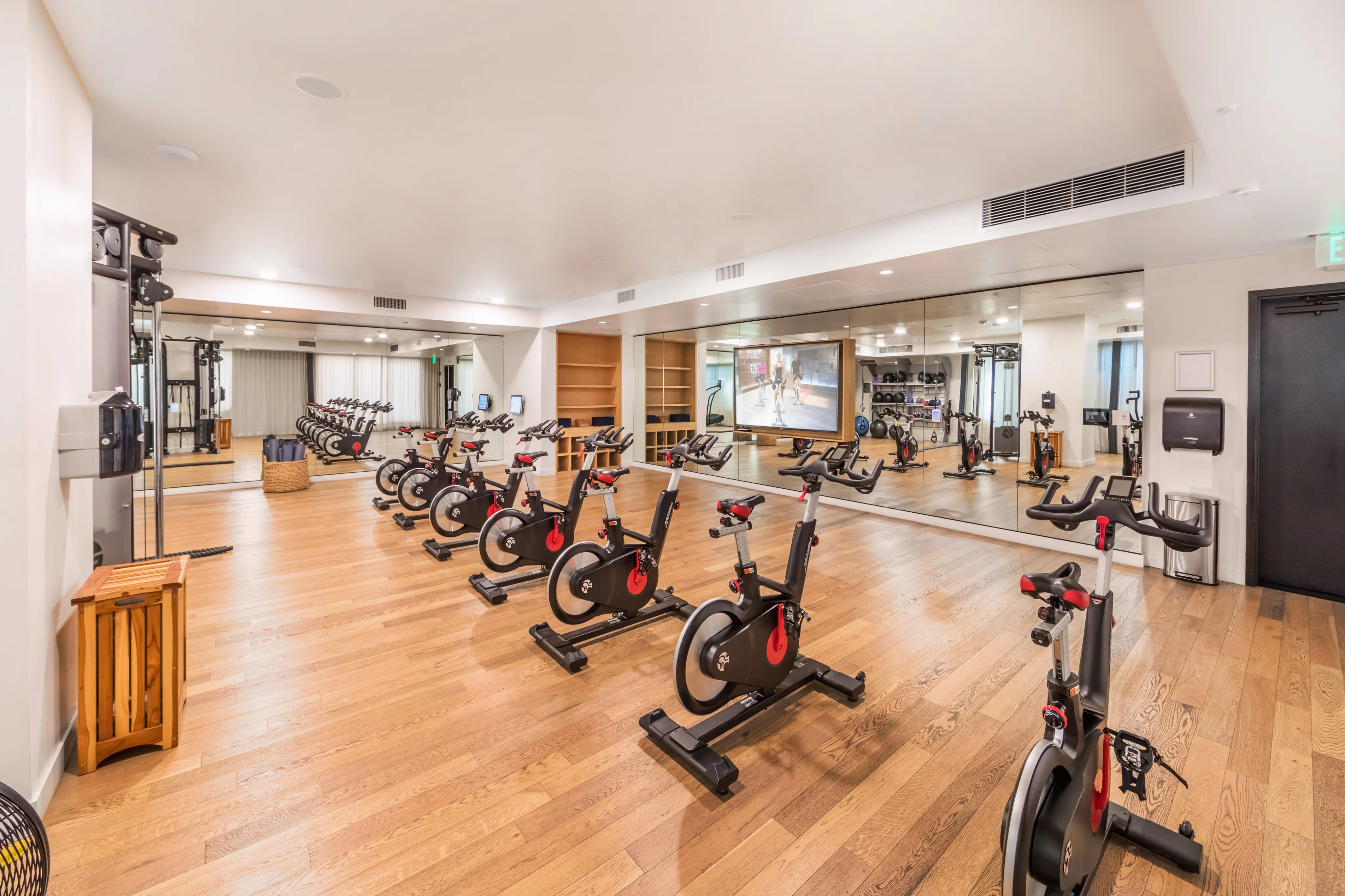 Modern fitness center with sleek stationary bikes, mirrored walls, and warm wood flooring, perfect for an invigorating workout.
