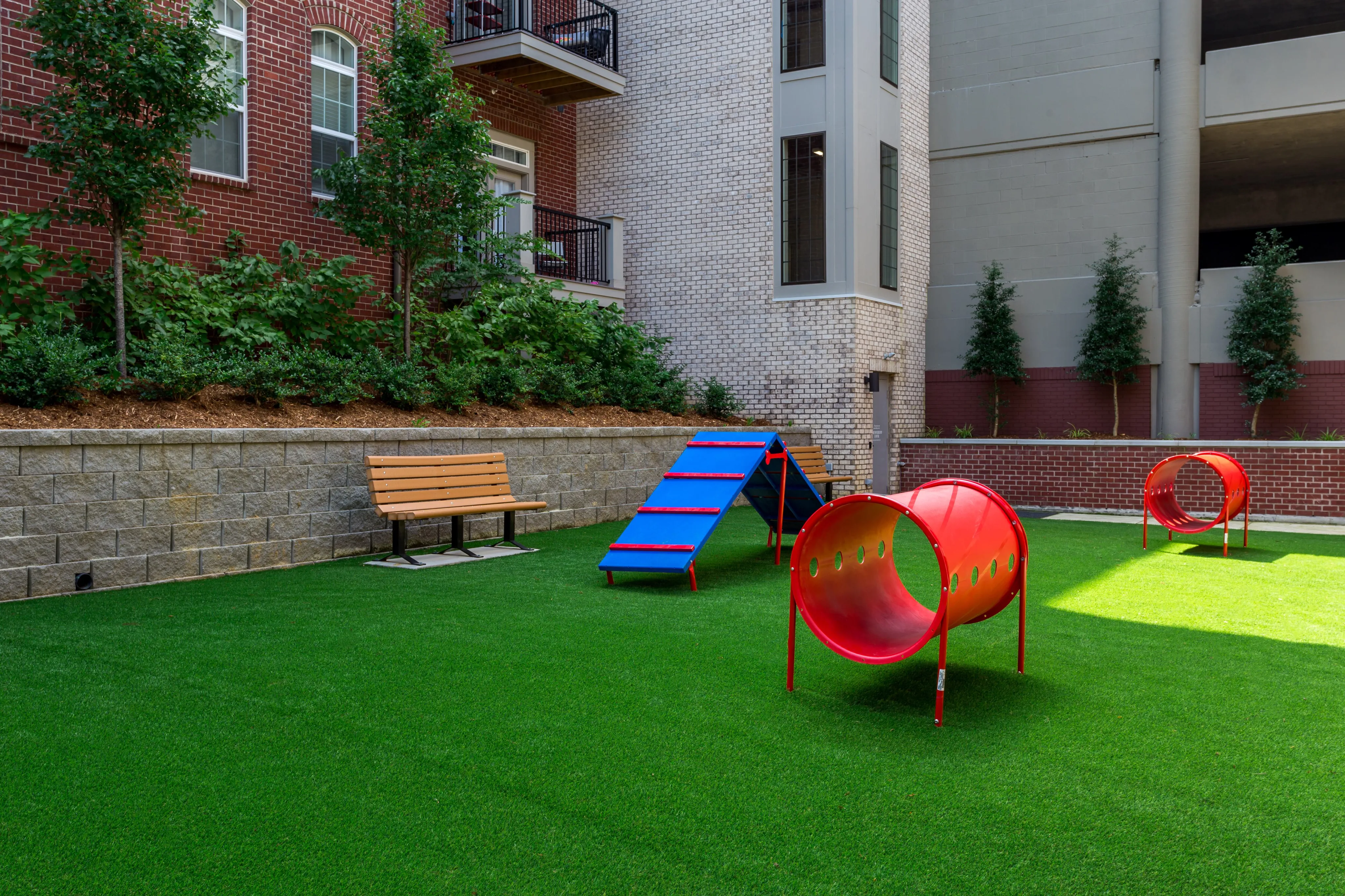 Charming urban playground featuring vibrant red and blue play structures on lush green turf, ideal for family enjoyment and relaxation.
