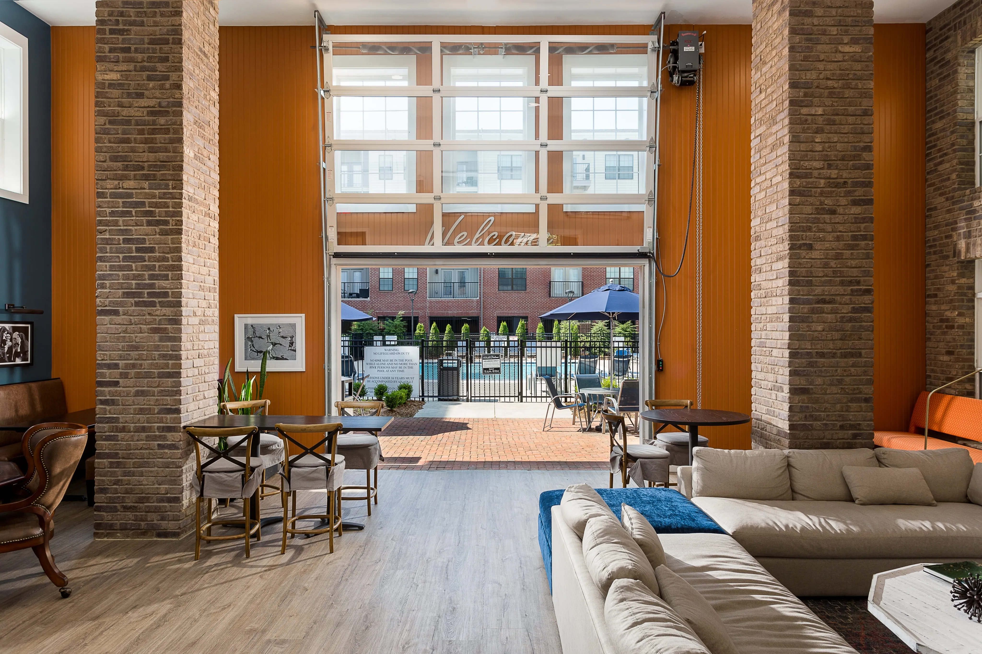 Bright and inviting lounge area with large windows, stylish furniture, and access to an outdoor pool. Perfect for relaxation and socializing.