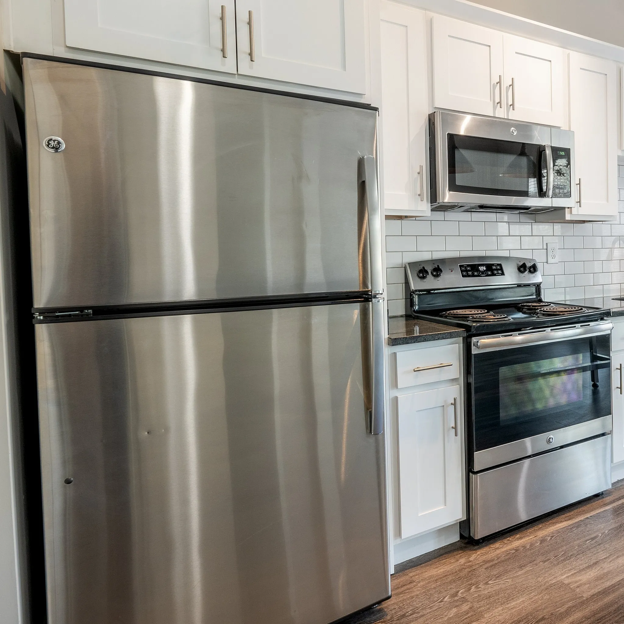 Contemporary kitchen with sleek stainless steel appliances, white cabinetry, and stylish pendant lighting, offering a bright and inviting culinary space.
