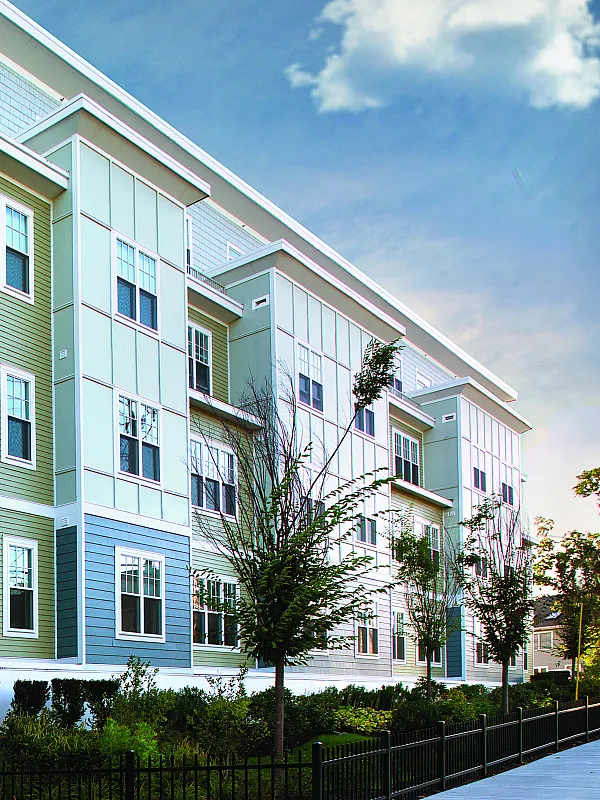 Elegant modern apartment building with a sleek design and lush landscaping under a bright blue sky.