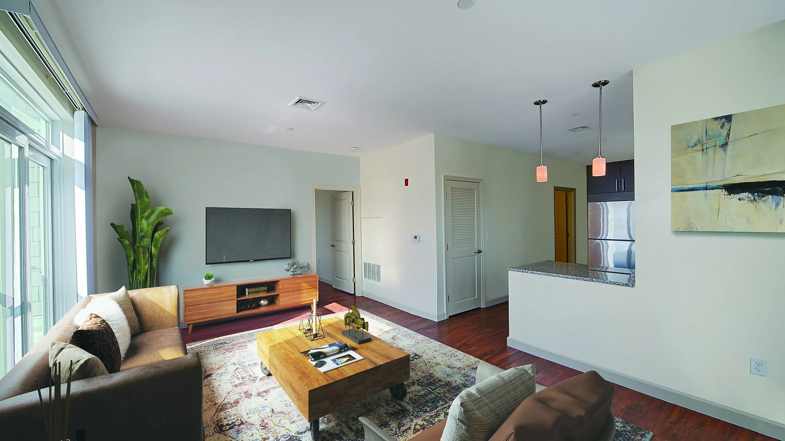 Chic and inviting living room with modern decor, large windows for natural light, and open kitchen with sleek countertops.
