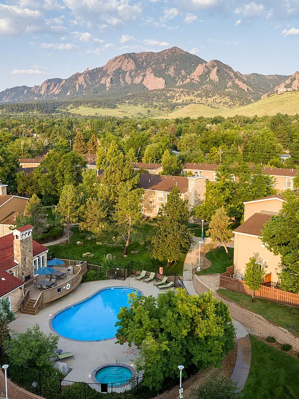 Charming apartment community nestled against picturesque mountains, featuring a sparkling pool and lush greenery.