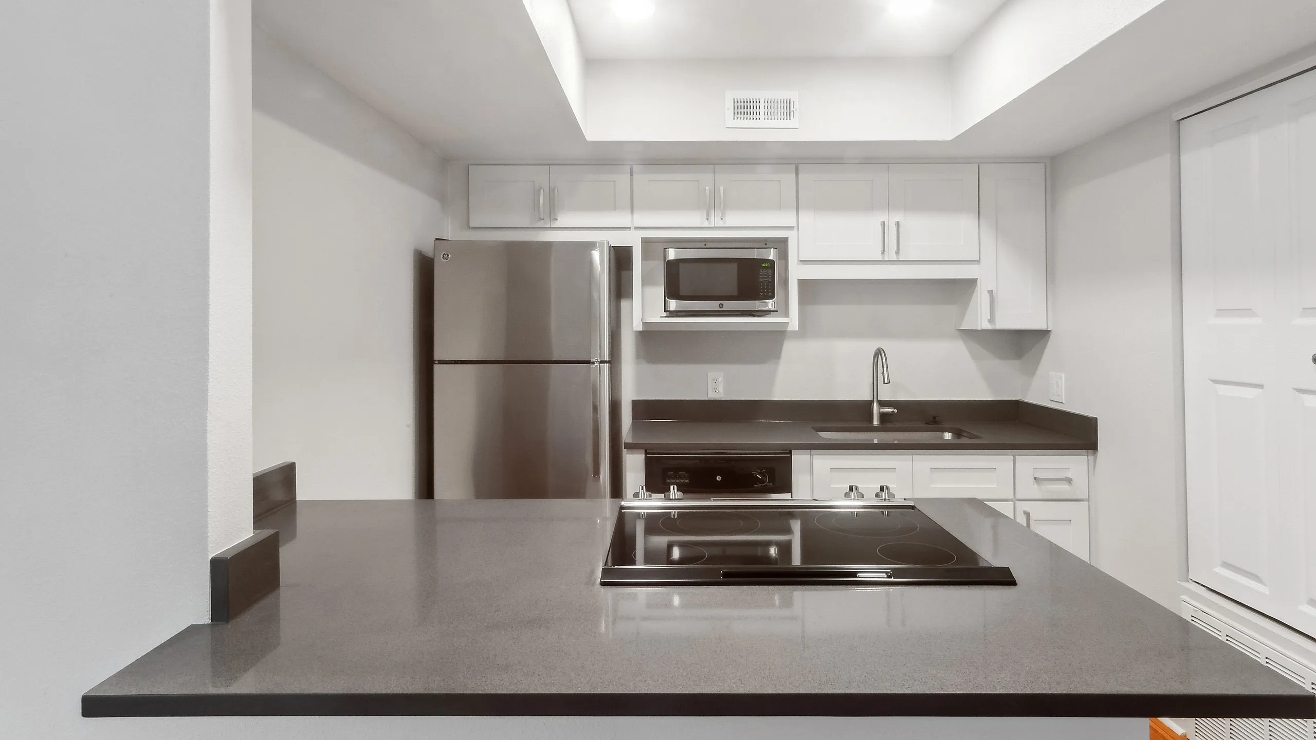 Modern kitchen with sleek stainless steel appliances, elegant white cabinetry, and a spacious countertop for a clean, contemporary feel.