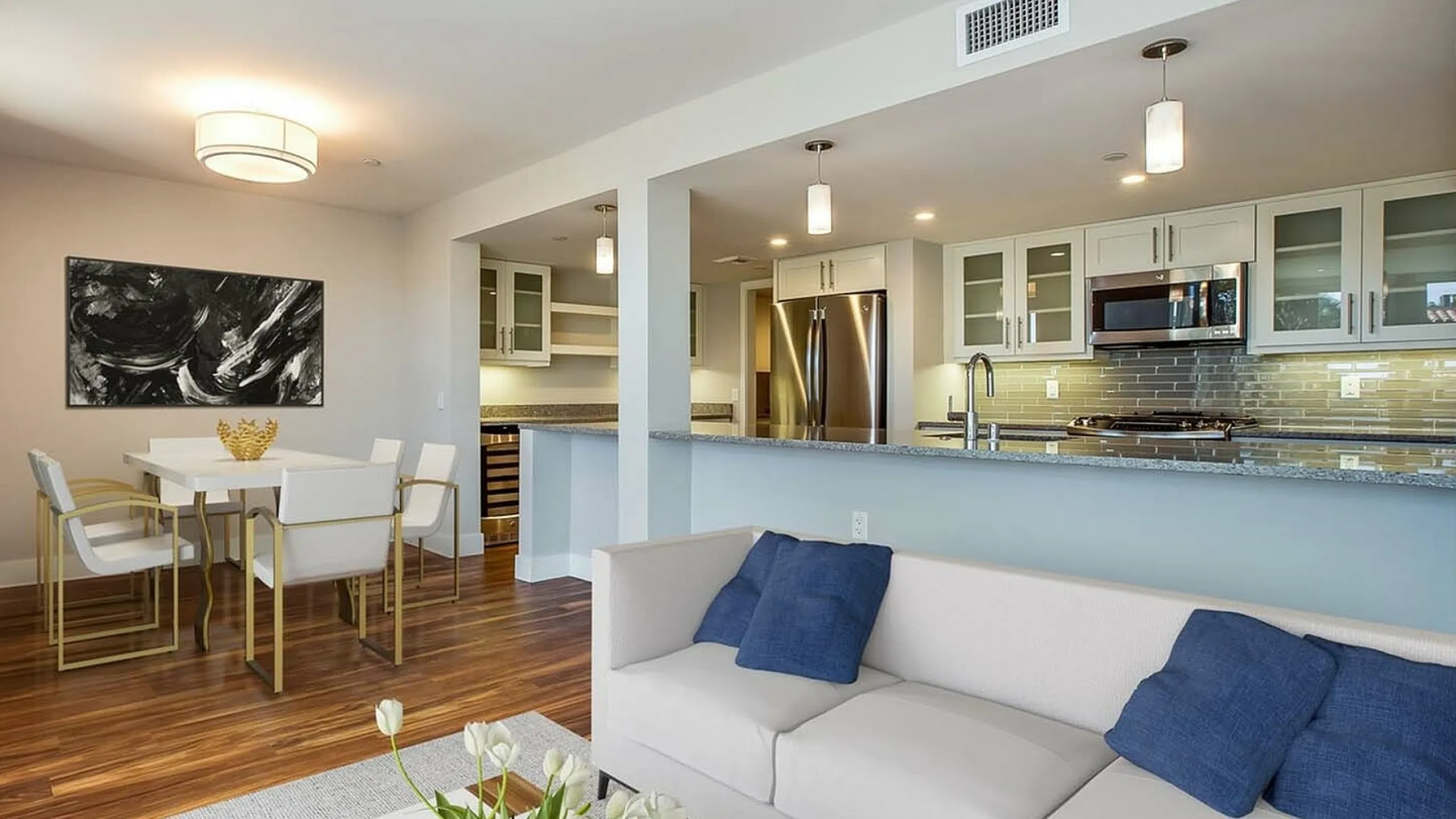 Modern open-concept living space showcasing a sleek kitchen with stainless steel appliances, a stylish dining area, and elegant hardwood floors.