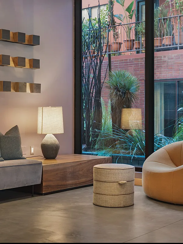 Elegant modern living room with cozy seating, stylish decor, and a lush garden view through the large glass window.