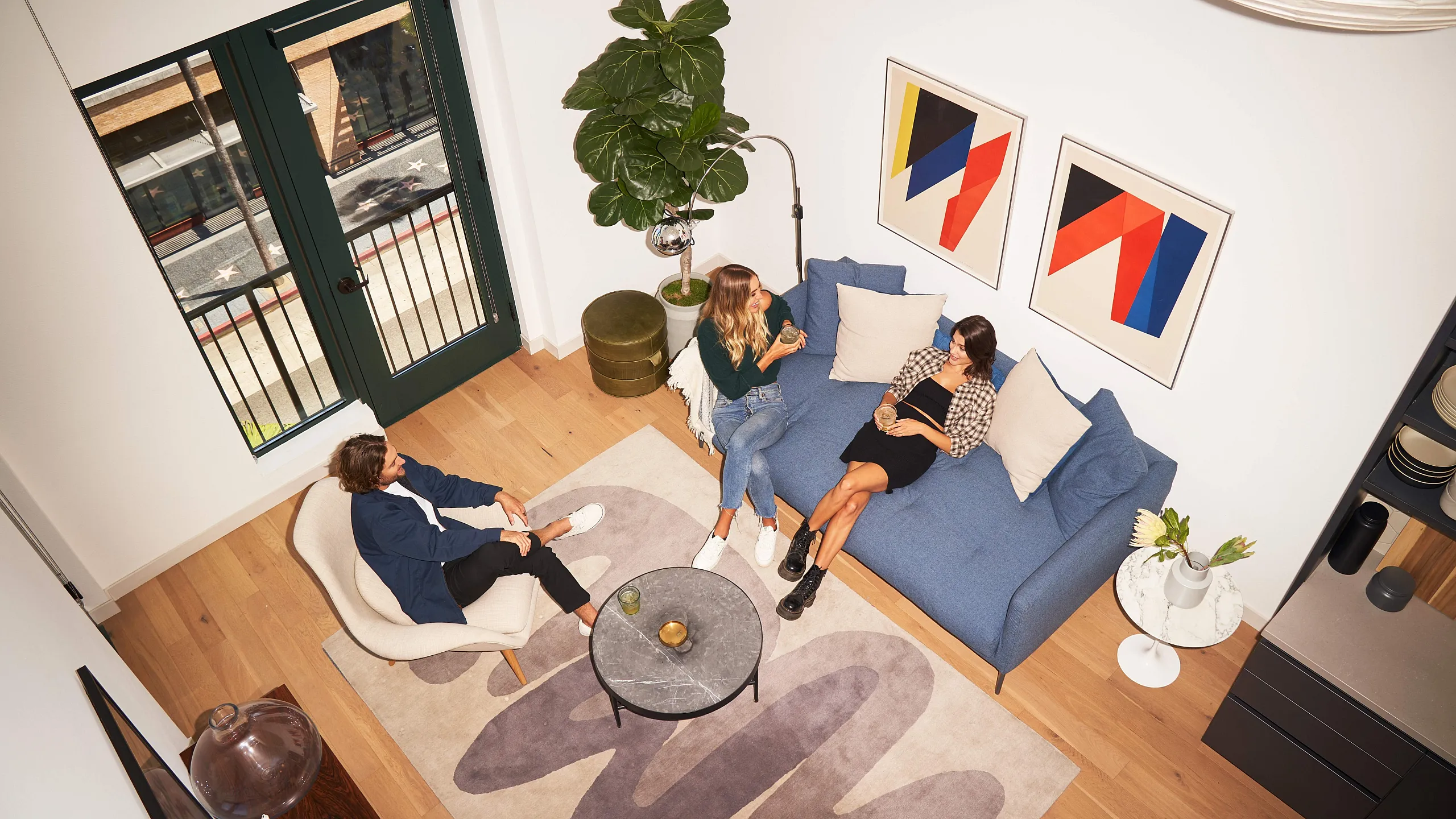 Chic urban living room with modern decor, blue sofa, and stylish art, perfect for social gatherings.