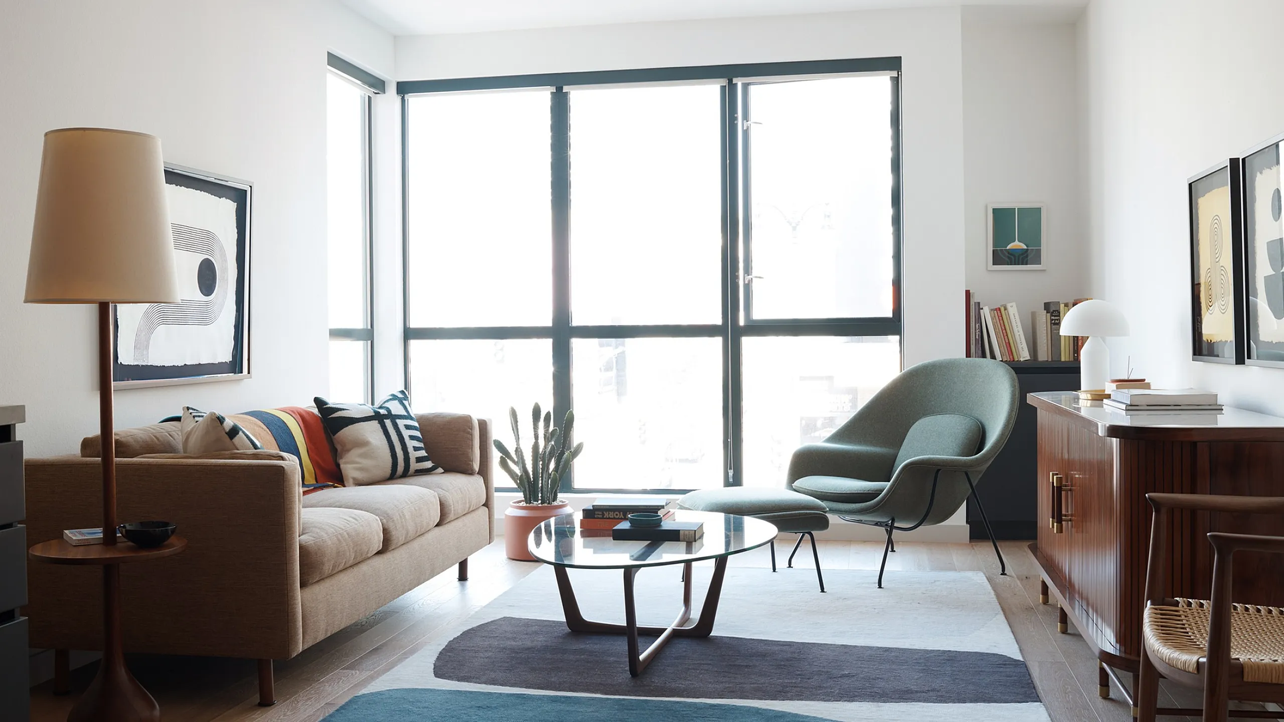 Bright and inviting living room with modern furniture, large windows, and artistic decor, perfect for relaxation.