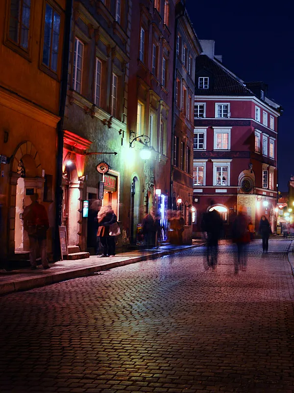 Charming cobblestone street scene at night with warmly lit historical buildings and a vibrant atmosphere.