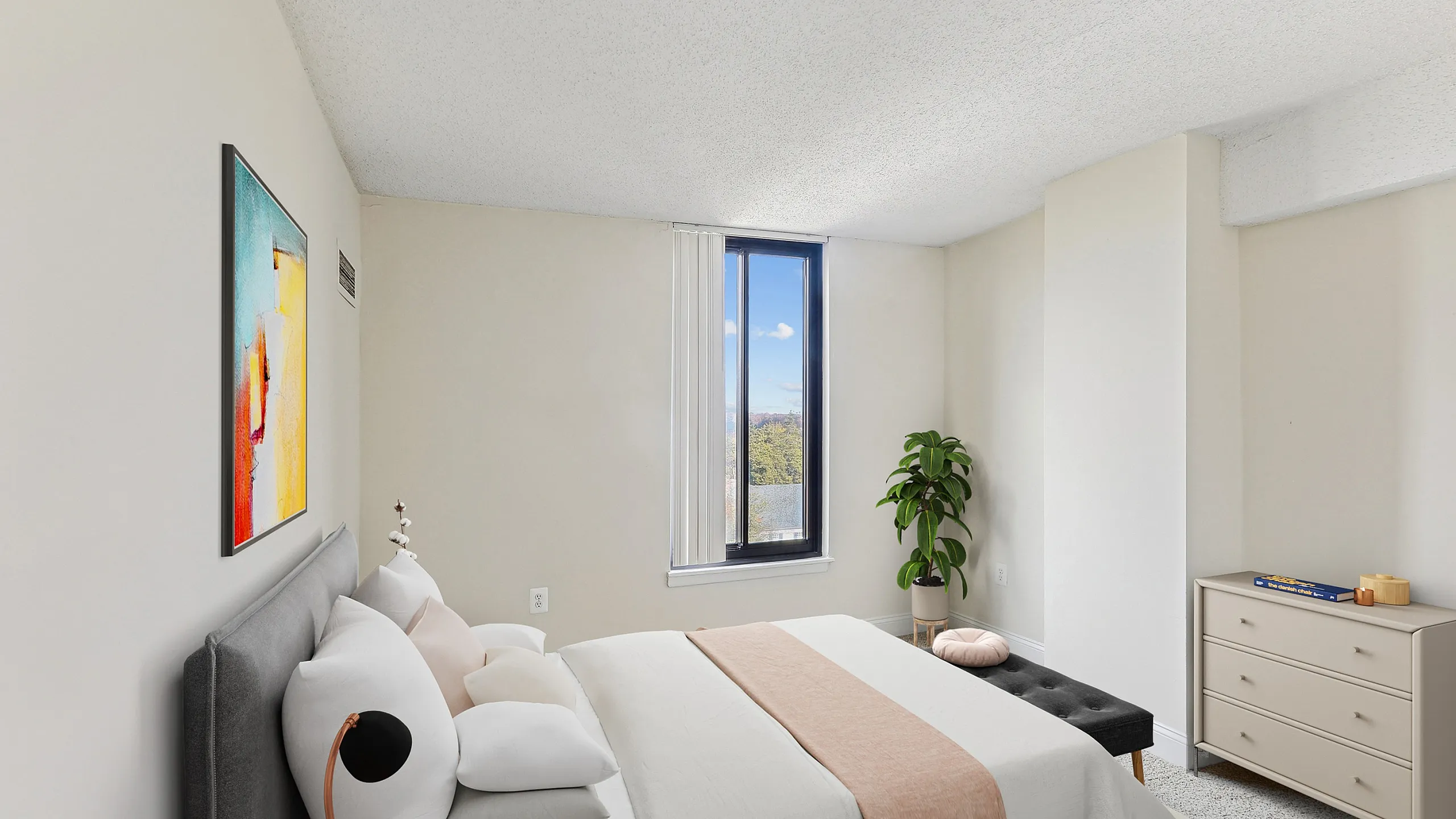 Bright and cozy bedroom with a minimalist design, showcasing a comfortable bed, modern art, and a large window letting in natural light.