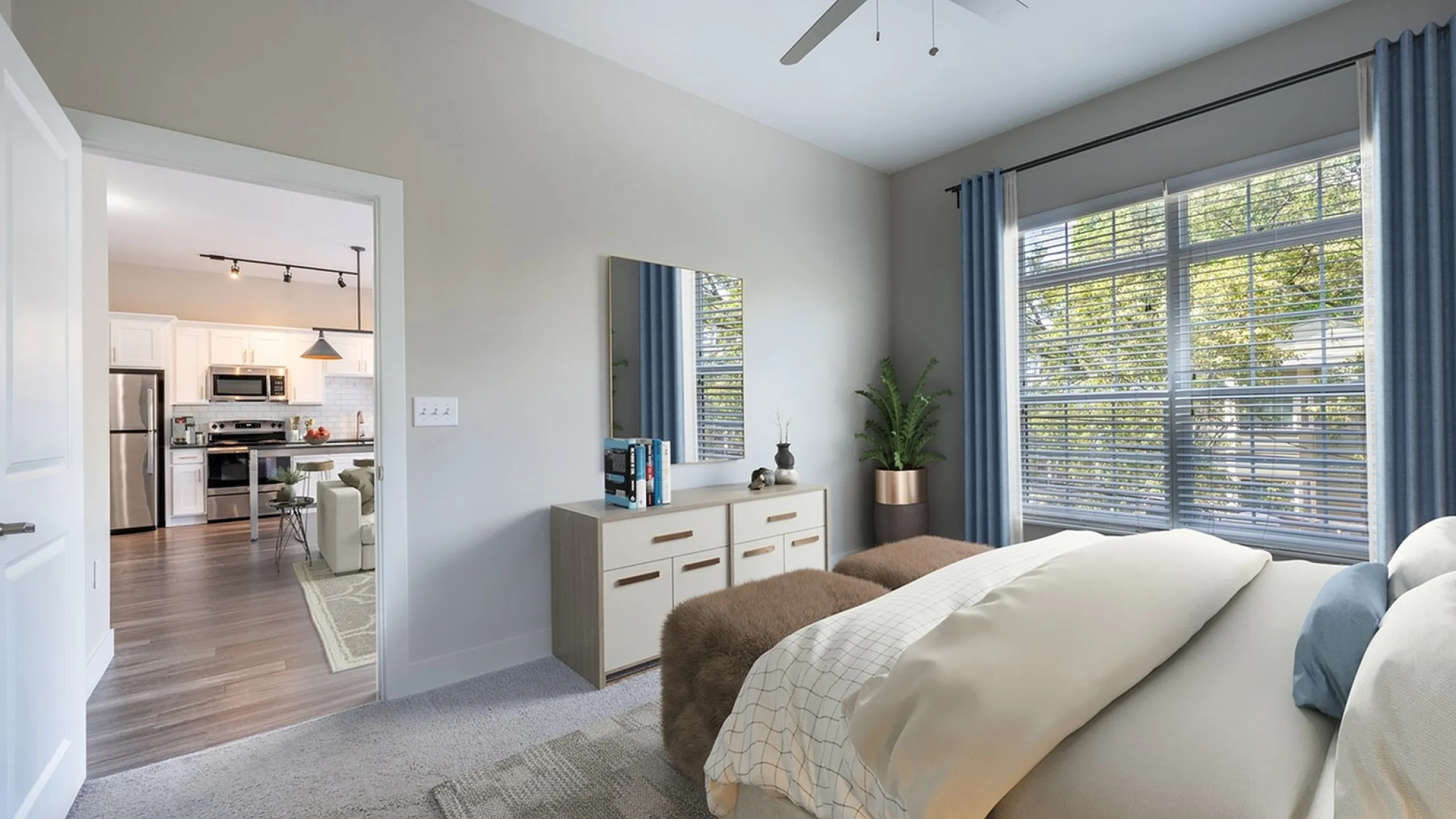 Inviting bedroom with elegant decor, plush bedding, and a view into a modern kitchen featuring stainless steel appliances.