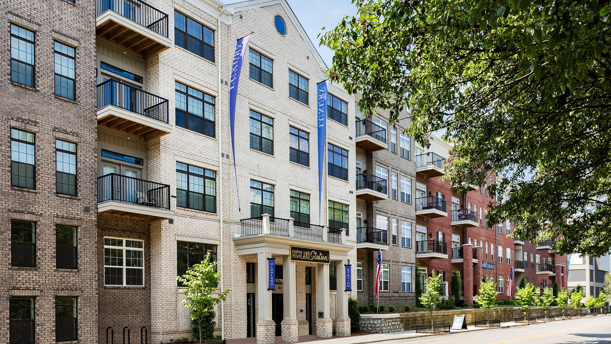 Charming urban apartment complex with modern brick facade, inviting balconies, and lush greenery, offering a perfect blend of style and comfort.