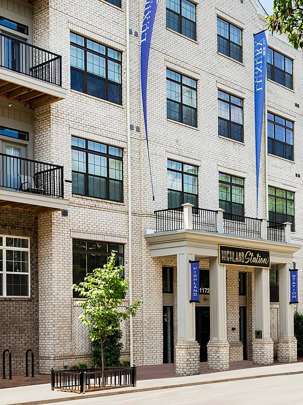 Charming urban apartment complex with stylish brick facade, featuring balconies and lush greenery, promising a vibrant living experience.