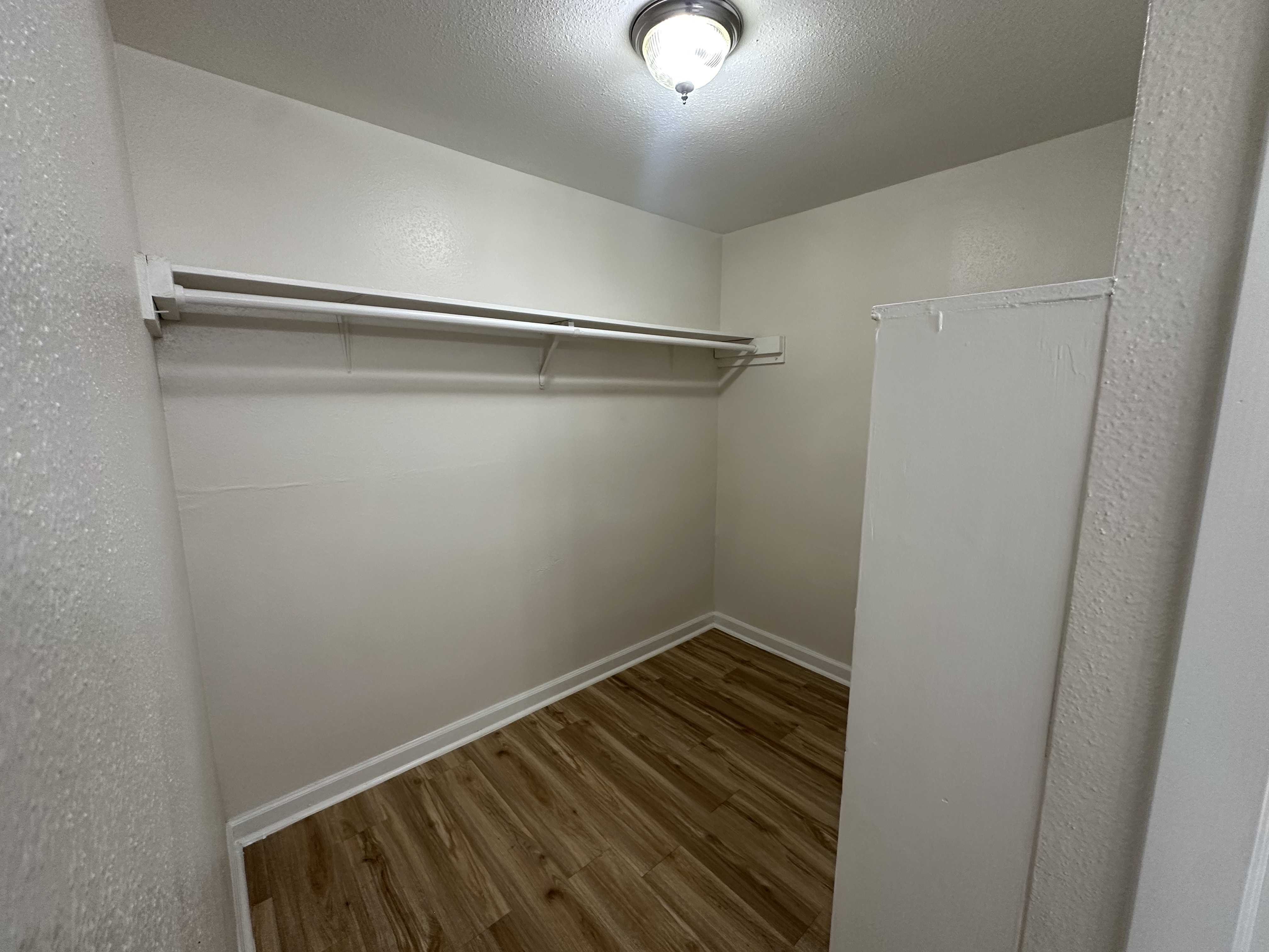 Spacious walk-in closet featuring modern lighting and elegant flooring.