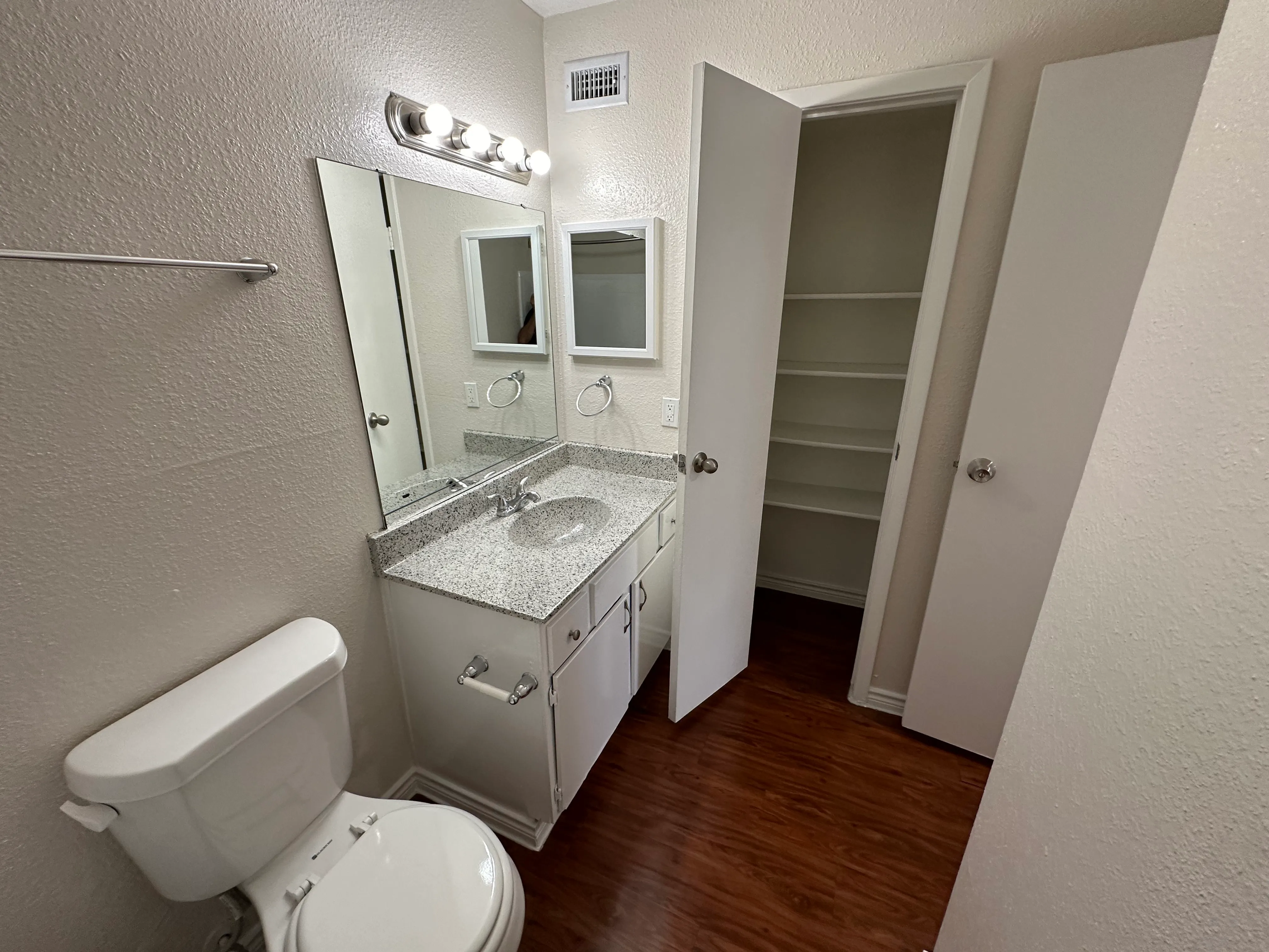 Contemporary bathroom featuring a sleek granite countertop, modern lighting, and a spacious linen closet.