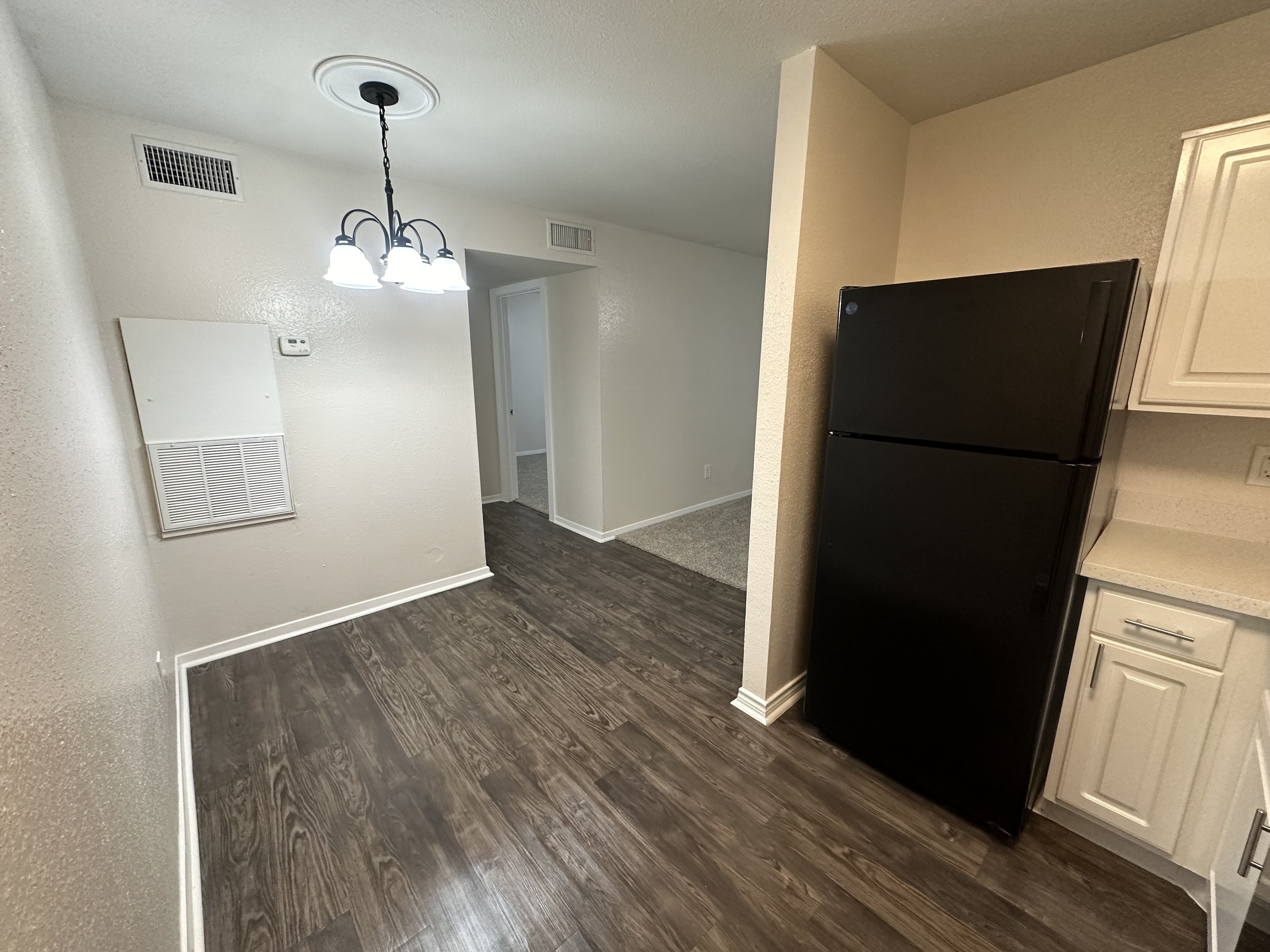 Bright and inviting kitchen space with elegant lighting, modern black refrigerator, and sleek flooring.
