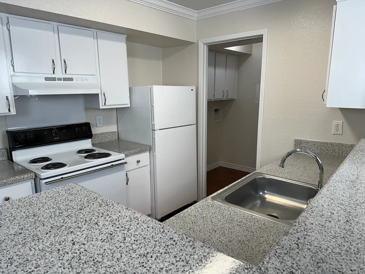 Modern kitchen with sleek countertops, stainless steel sink, and crisp white cabinetry.