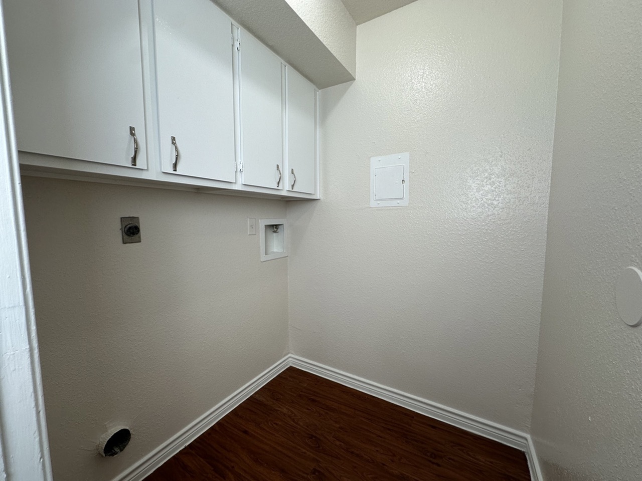Cozy laundry nook with sleek white cabinets, ready for customization.