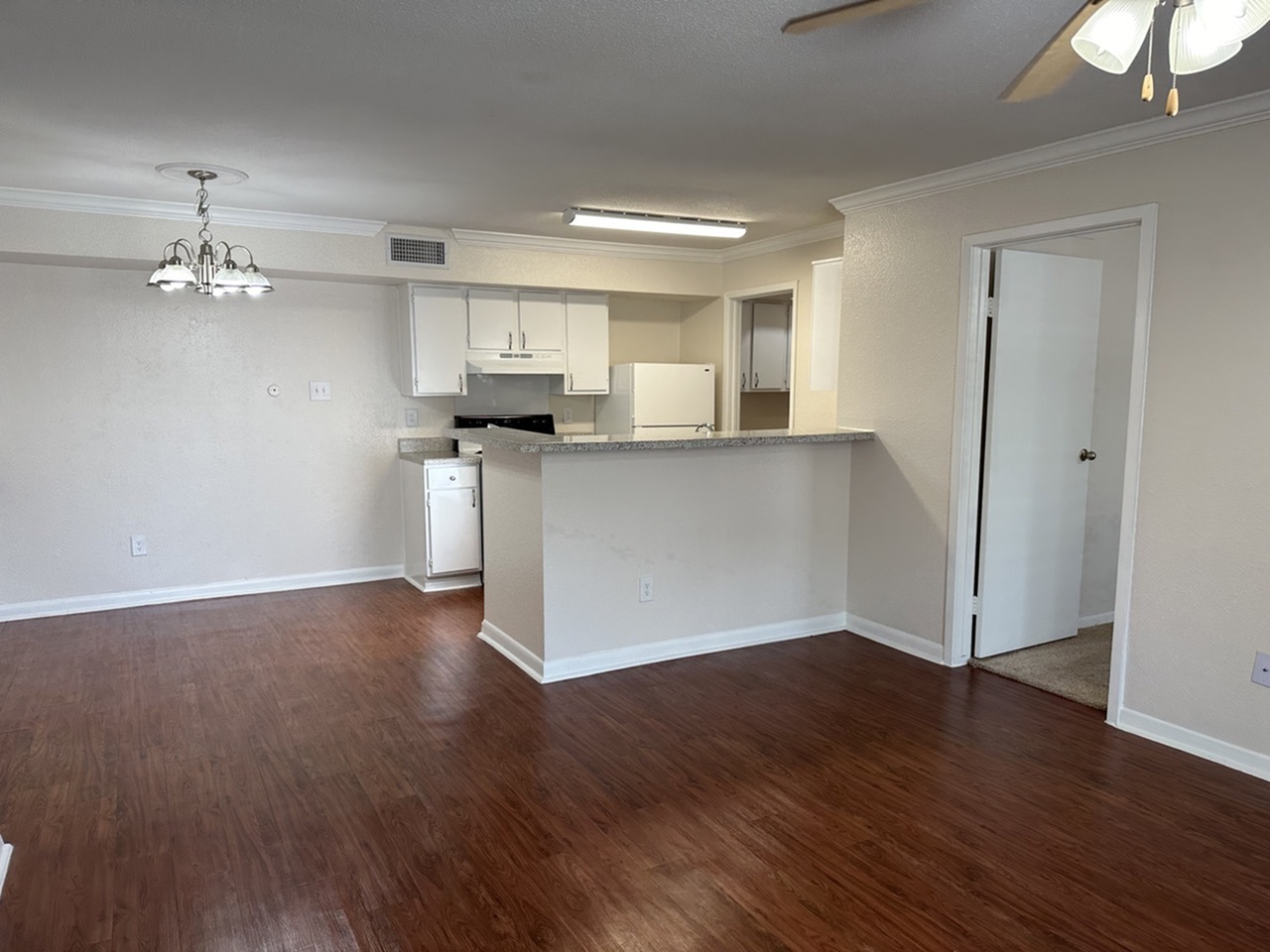 Inviting open-plan living area with elegant wood-style flooring, spacious kitchen, and modern lighting accents.