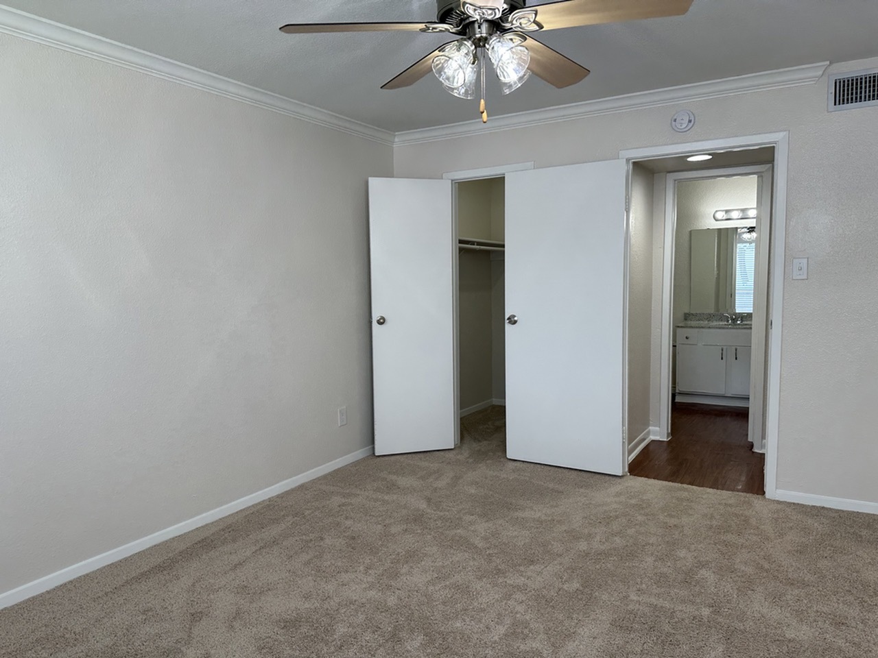 Bright bedroom with a ceiling fan, spacious closet, and convenient access to bathroom featuring modern fixtures.