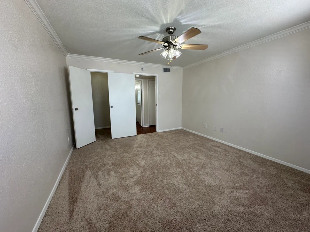 Spacious bedroom with plush carpet, ceiling fan, and ample natural light.