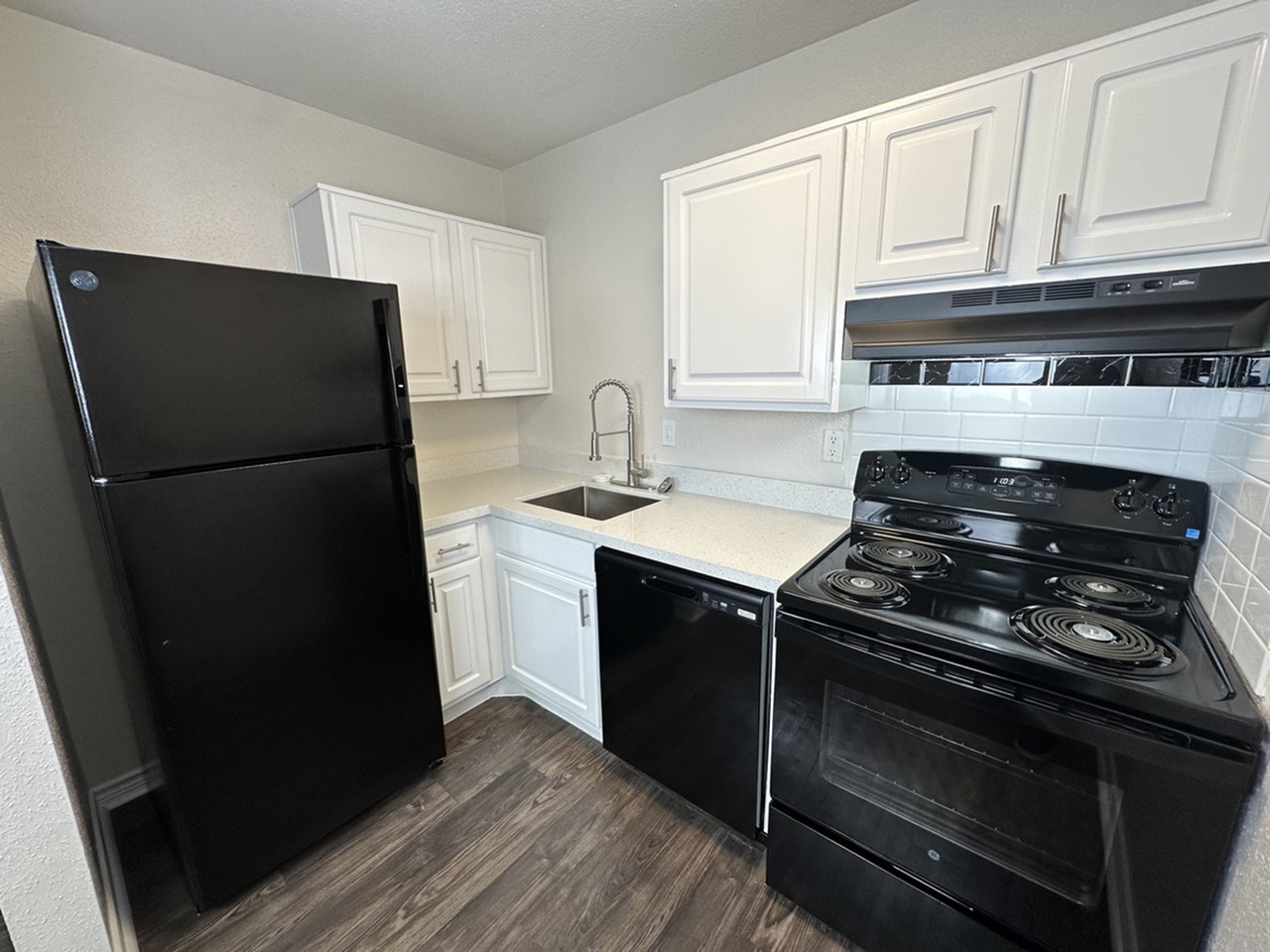 Modern kitchen with sleek black appliances, elegant white cabinetry, and a glossy quartz countertop, offering a blend of style and functionality.
