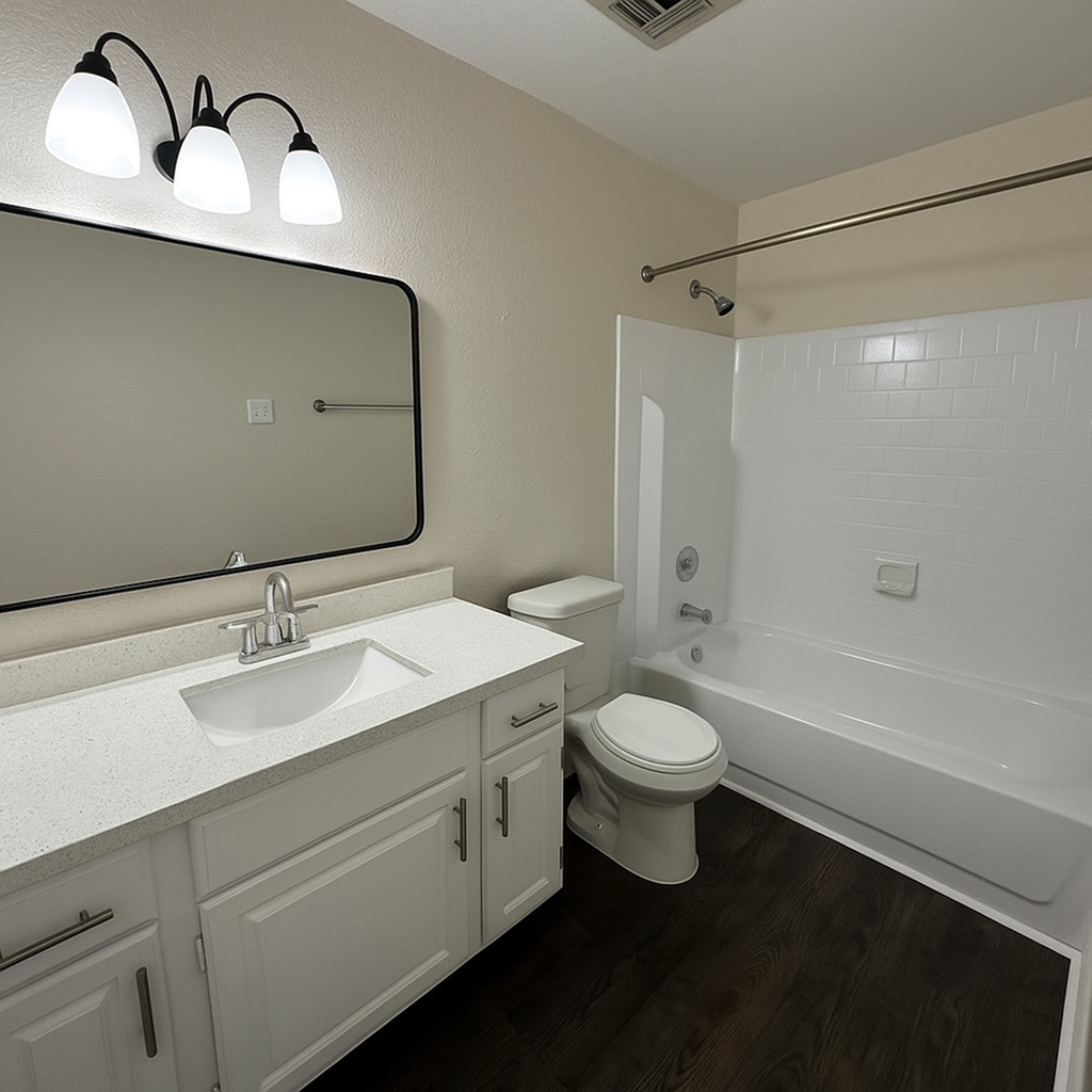 Modern bathroom featuring a sleek white vanity, elegant lighting, and a spacious bathtub with dark wood-style flooring.