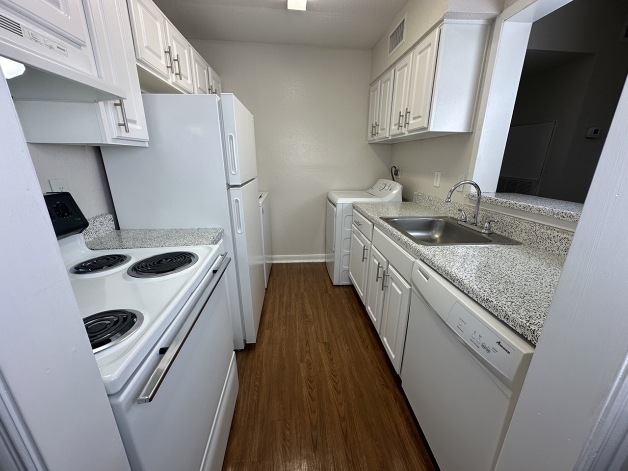 Modern kitchen featuring sleek white cabinetry, elegant countertops, and wood flooring with integrated appliances.