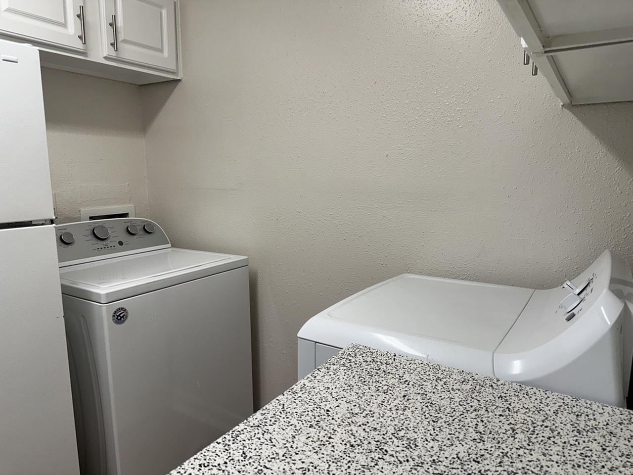Modern laundry area with washer and dryer, featuring sleek cabinets in a compact space.