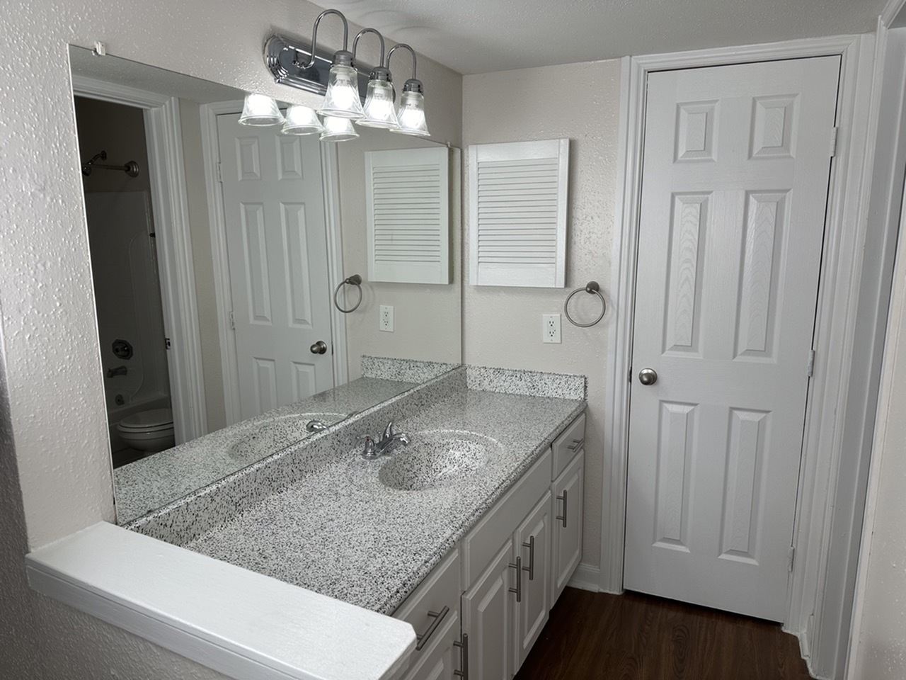 Modern bathroom featuring a sleek countertop, stylish lighting, and ample storage with white cabinetry.