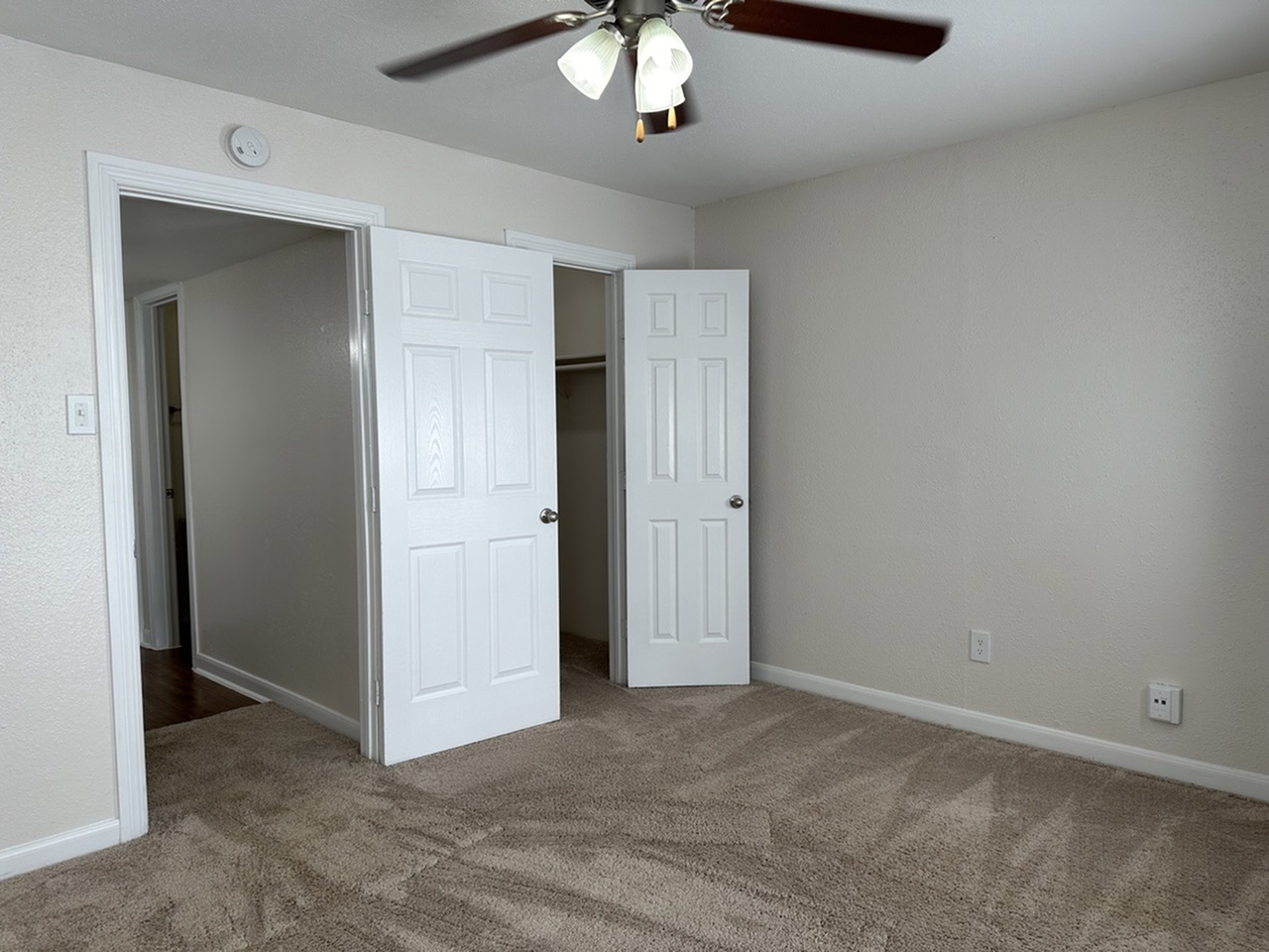 Cozy bedroom with plush carpeting, ceiling fan, and walk-in closet offering ample storage space.