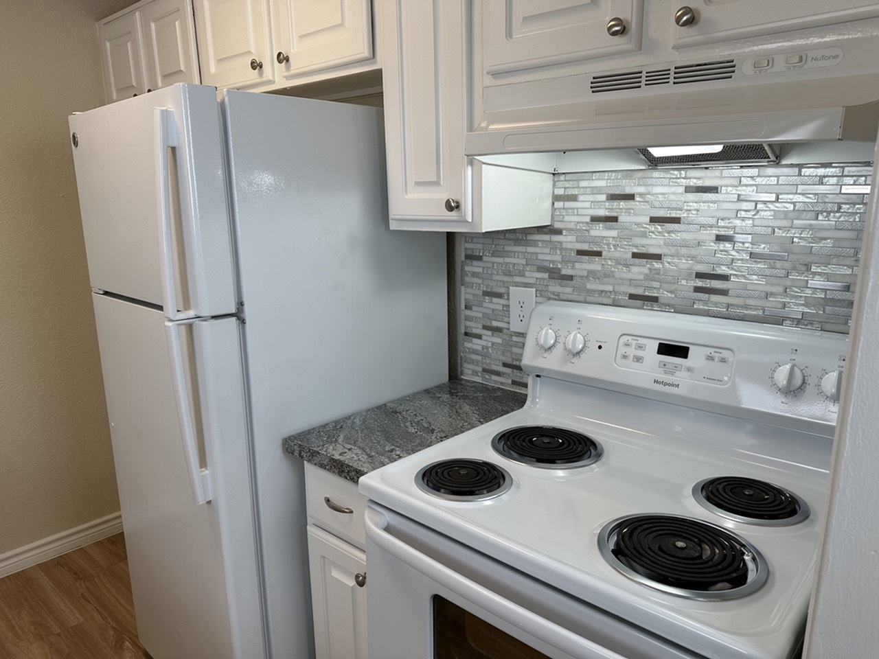 Modern kitchen featuring a sleek stovetop, elegant tile backsplash, and ample cabinet space.