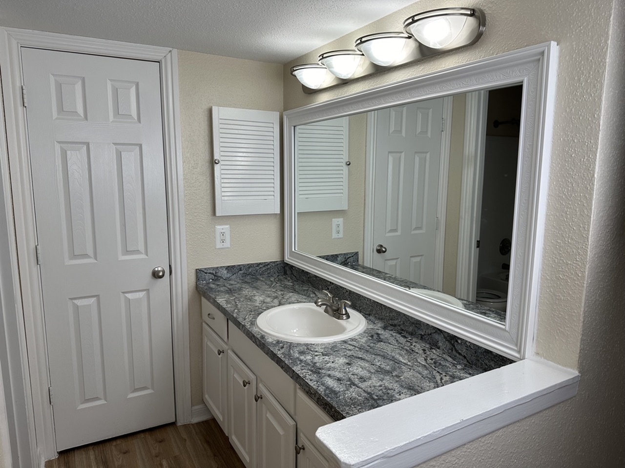 Elegant bathroom with sleek modern countertop, spacious mirror, and stylish lighting, offering a bright and fresh ambiance.