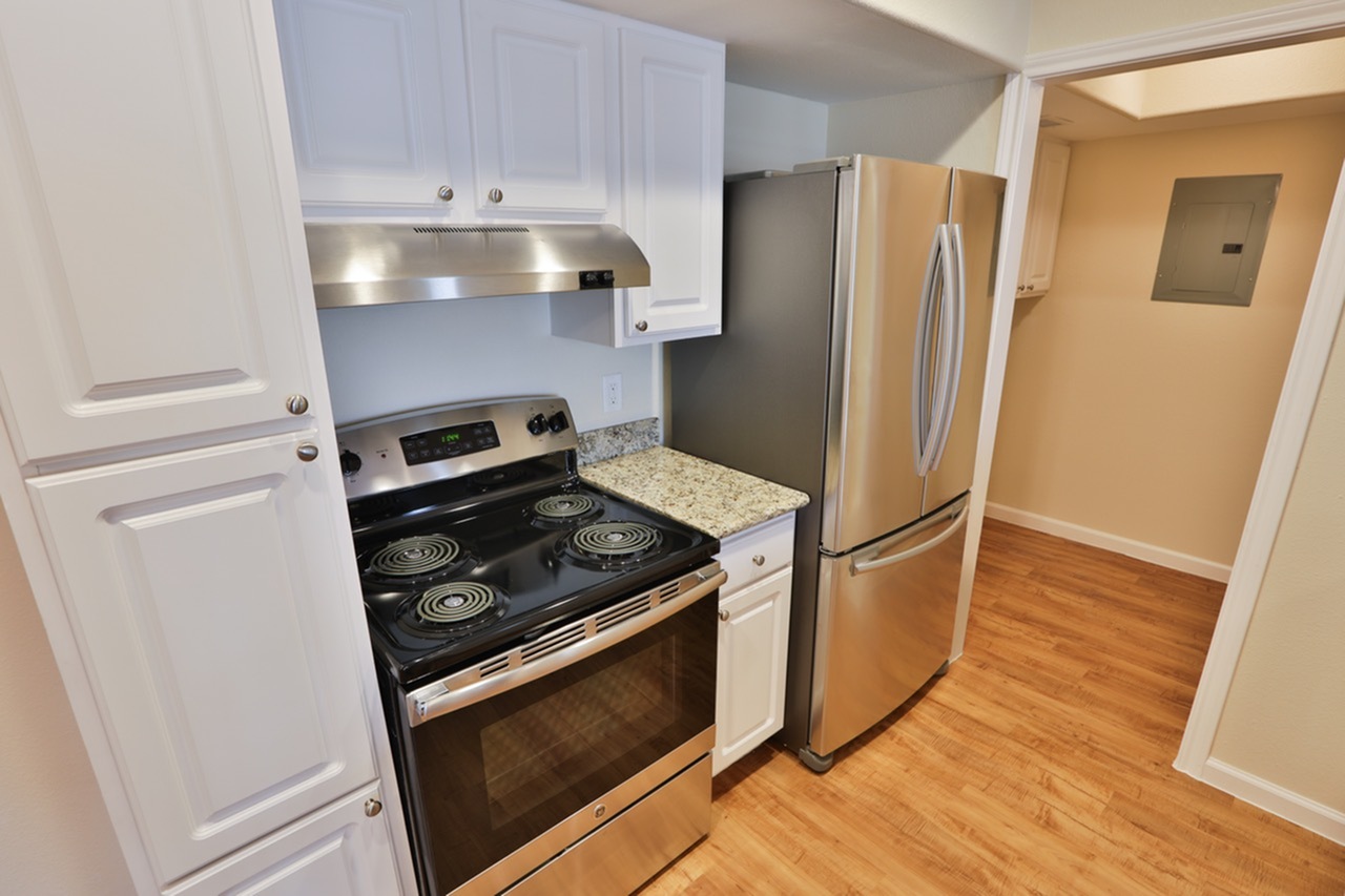 Contemporary kitchen with stainless steel appliances, sleek countertops, and elegant white cabinetry.