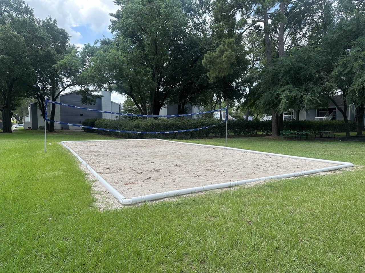 Inviting outdoor sand volleyball court surrounded by lush greenery, perfect for recreation and relaxation.