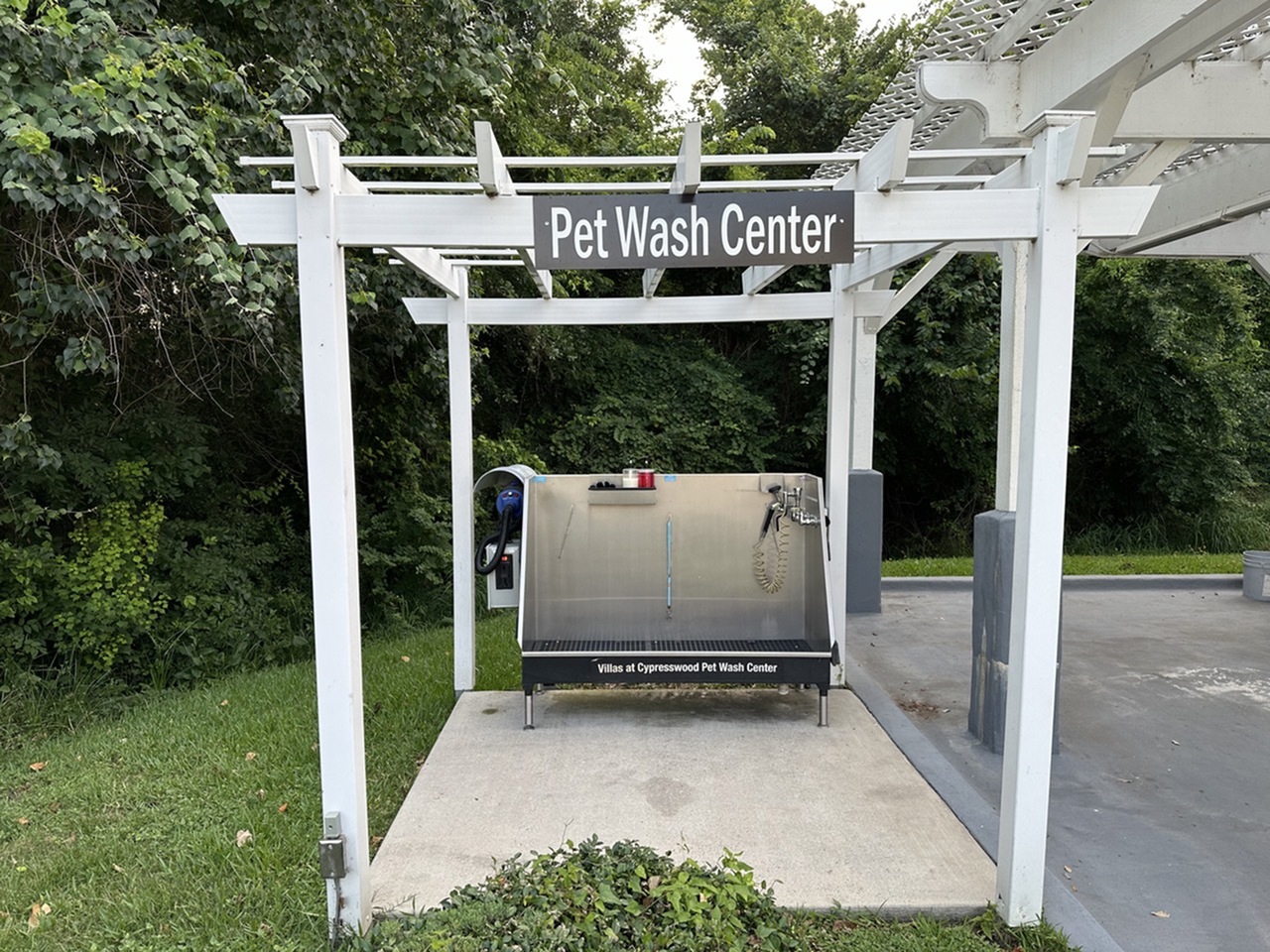 Charming pet wash center nestled in lush greenery, featuring a modern washing station under a stylish white pergola.