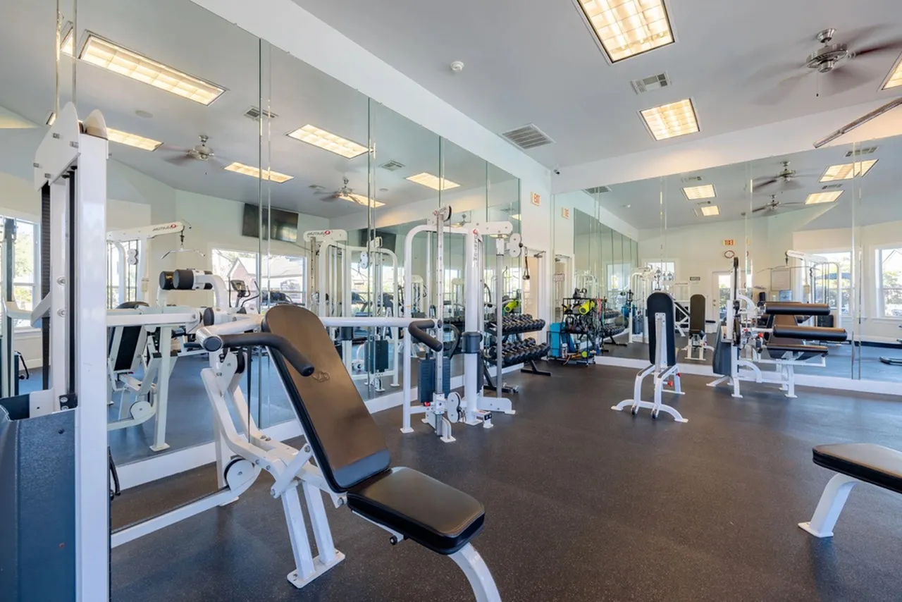 Modern fitness center with top-of-the-line equipment, mirrored walls, and ample natural light for a refreshing workout experience.