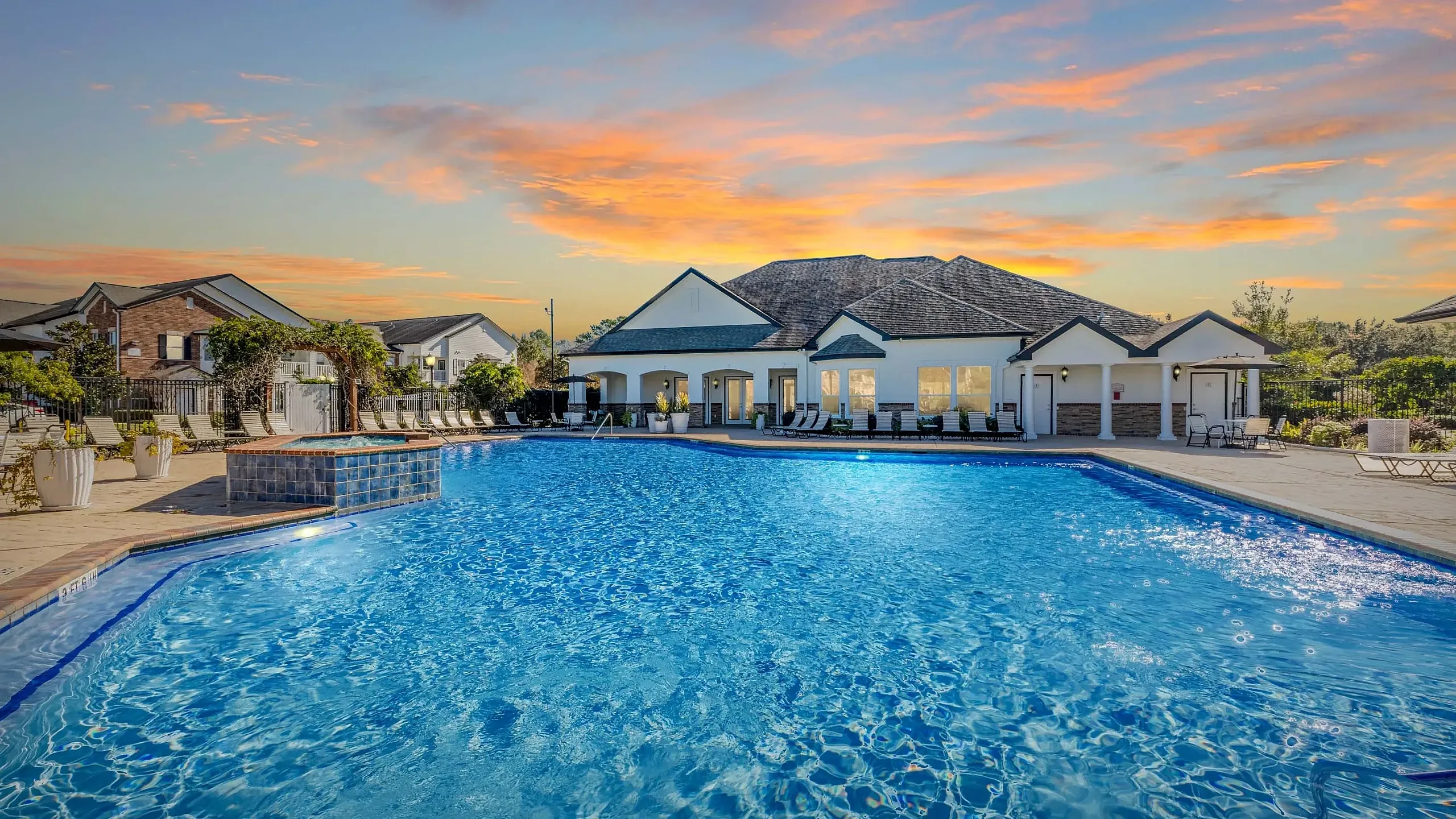 Luxurious apartment complex showcasing a stunning resort-style pool with a sunset backdrop.