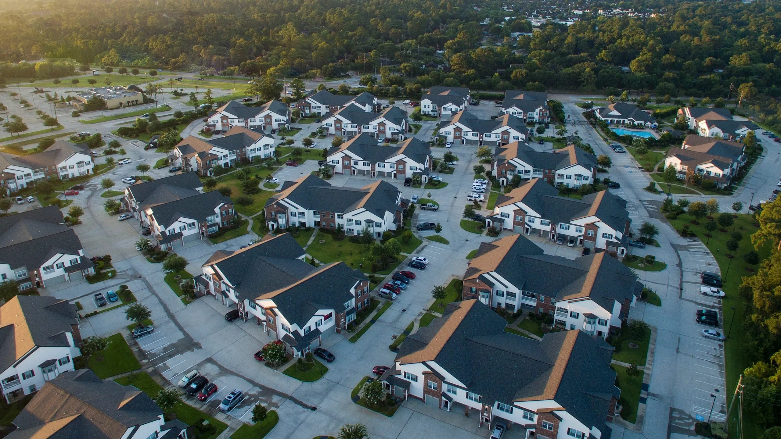 Scenic aerial view of a charming suburban neighborhood featuring modern multi-story homes surrounded by lush greenery and winding roads.