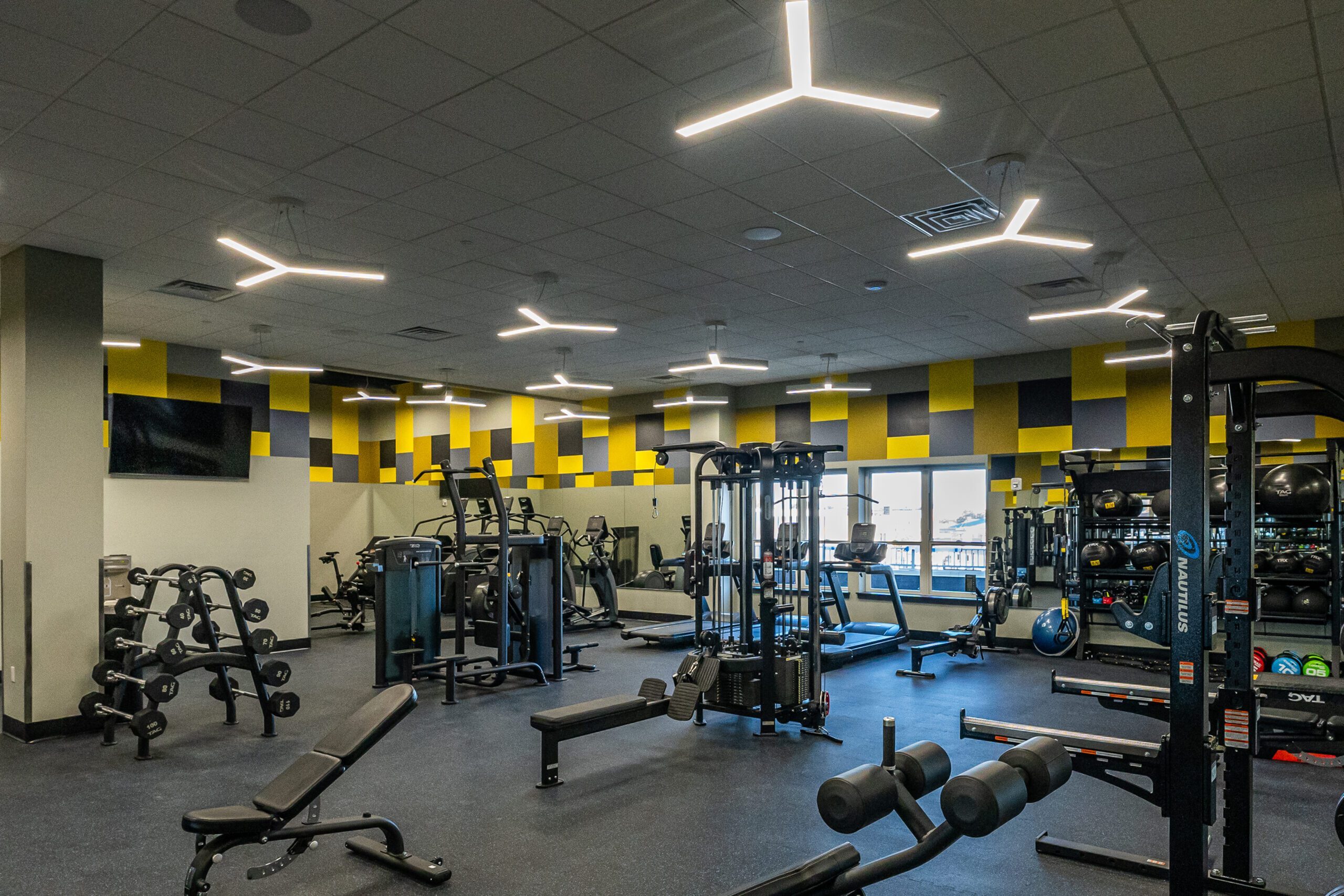 Modern gym facility with diverse equipment, sleek design, and vibrant yellow accents, perfect for fitness enthusiasts.
