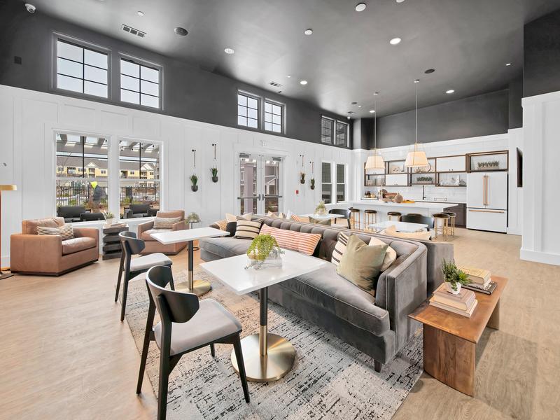 Luxurious open-concept living space with chic decor, featuring a cozy seating area and a modern kitchen, bathed in natural light from large windows.