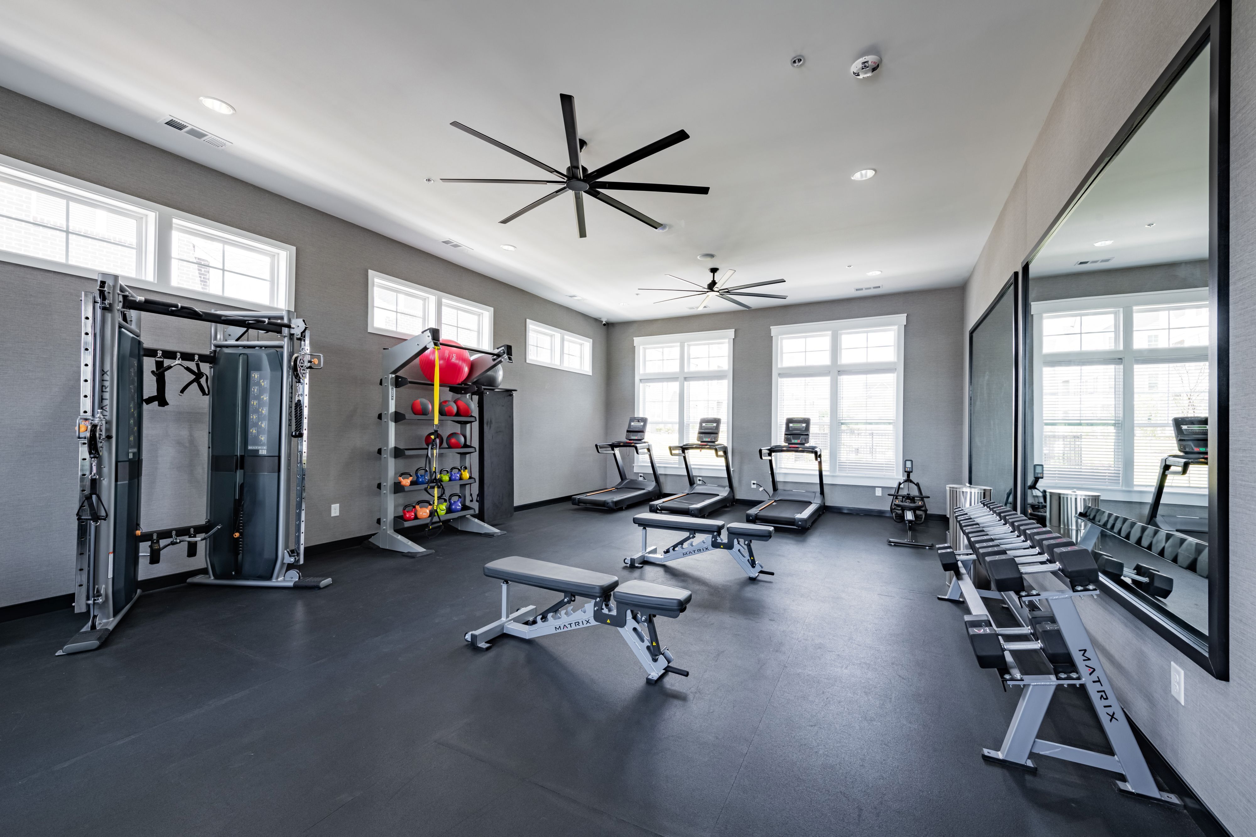 Modern apartment gym with state-of-the-art fitness equipment, including treadmills, weights, and exercise machines in a bright, spacious setting.