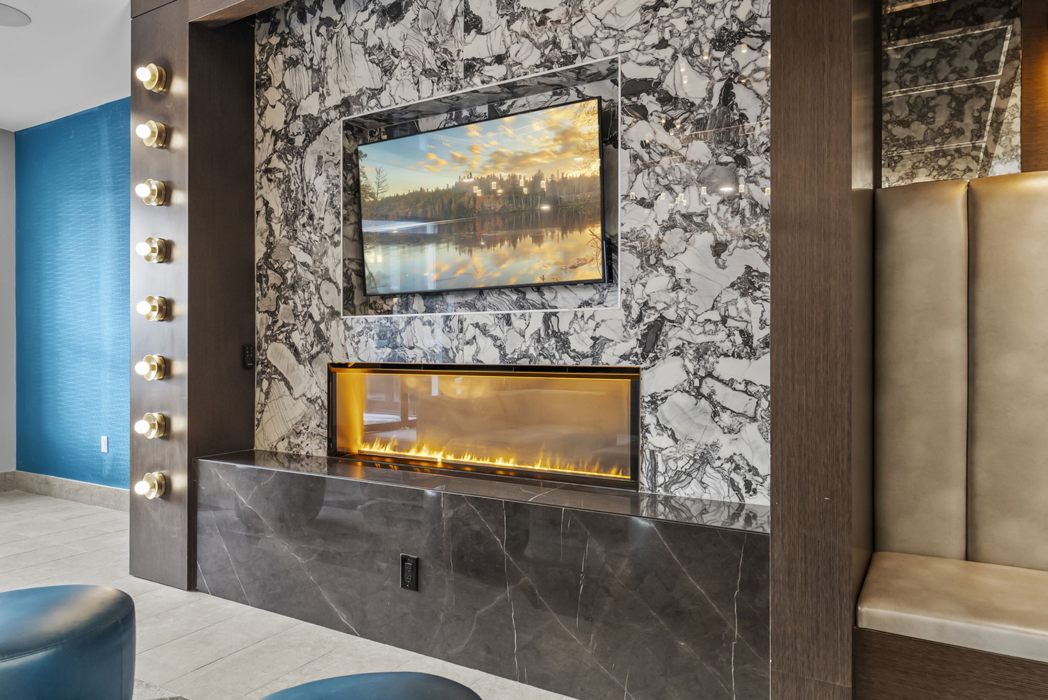 Luxurious modern interior featuring a sleek marble wall with a mounted TV above a stylish linear fireplace, complemented by elegant lighting accents.