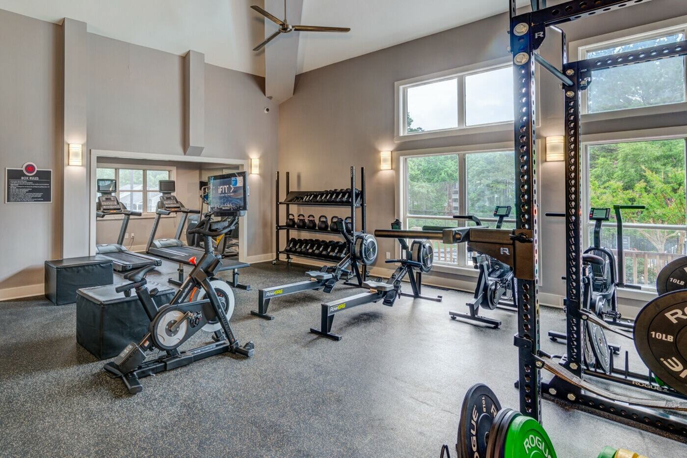 Bright and inviting apartment gym featuring modern exercise equipment, large windows, and spacious layout for a perfect workout experience.