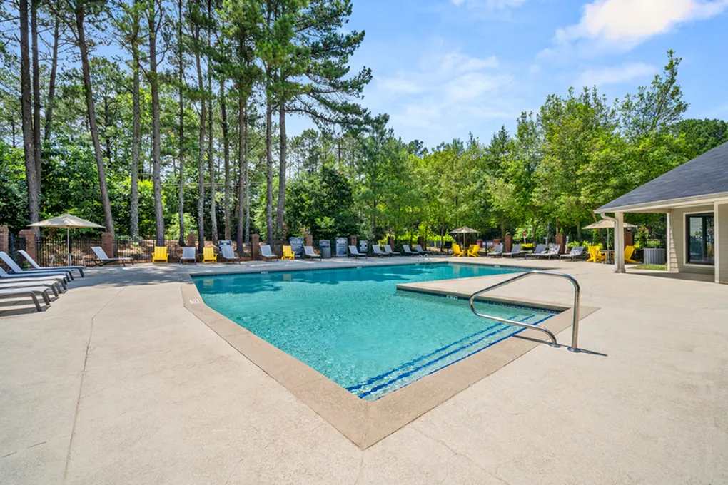 Inviting outdoor swimming pool surrounded by lush greenery and stylish lounge chairs, perfect for relaxation and entertainment.