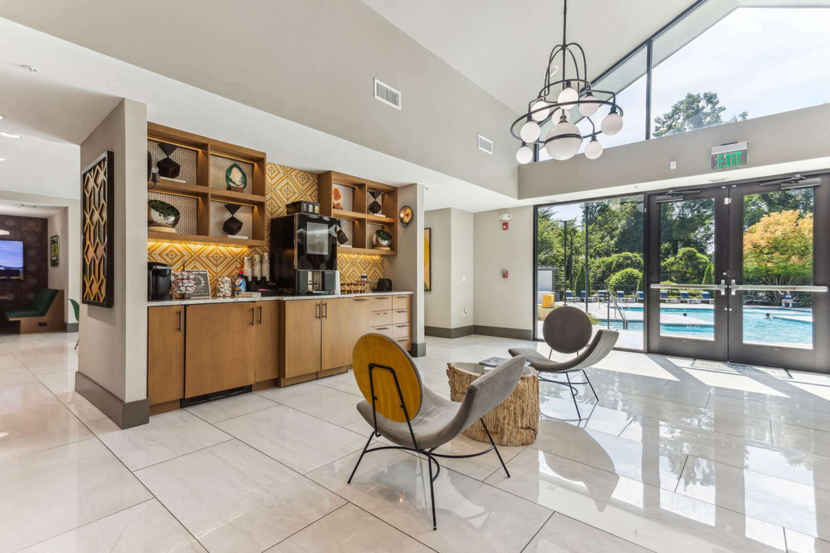 Spacious and modern lounge area featuring elegant seating, stylish decor, and a view of the inviting outdoor pool area through large glass doors.