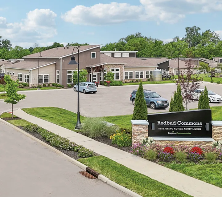Entrance of Redbud Commons, showcasing modern architecture in a serene, landscaped environment ideal for active adult living.